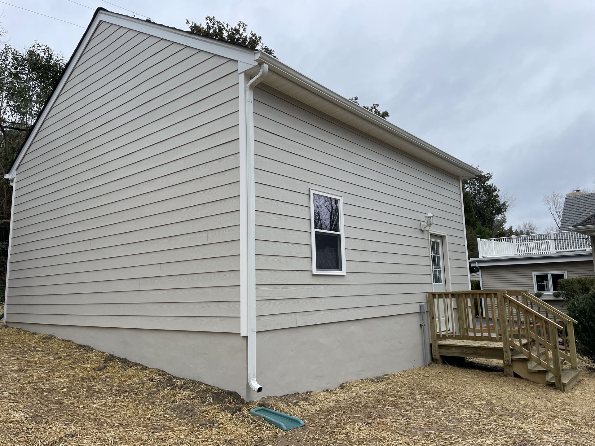 A small house with a deck and stairs on the side of it.