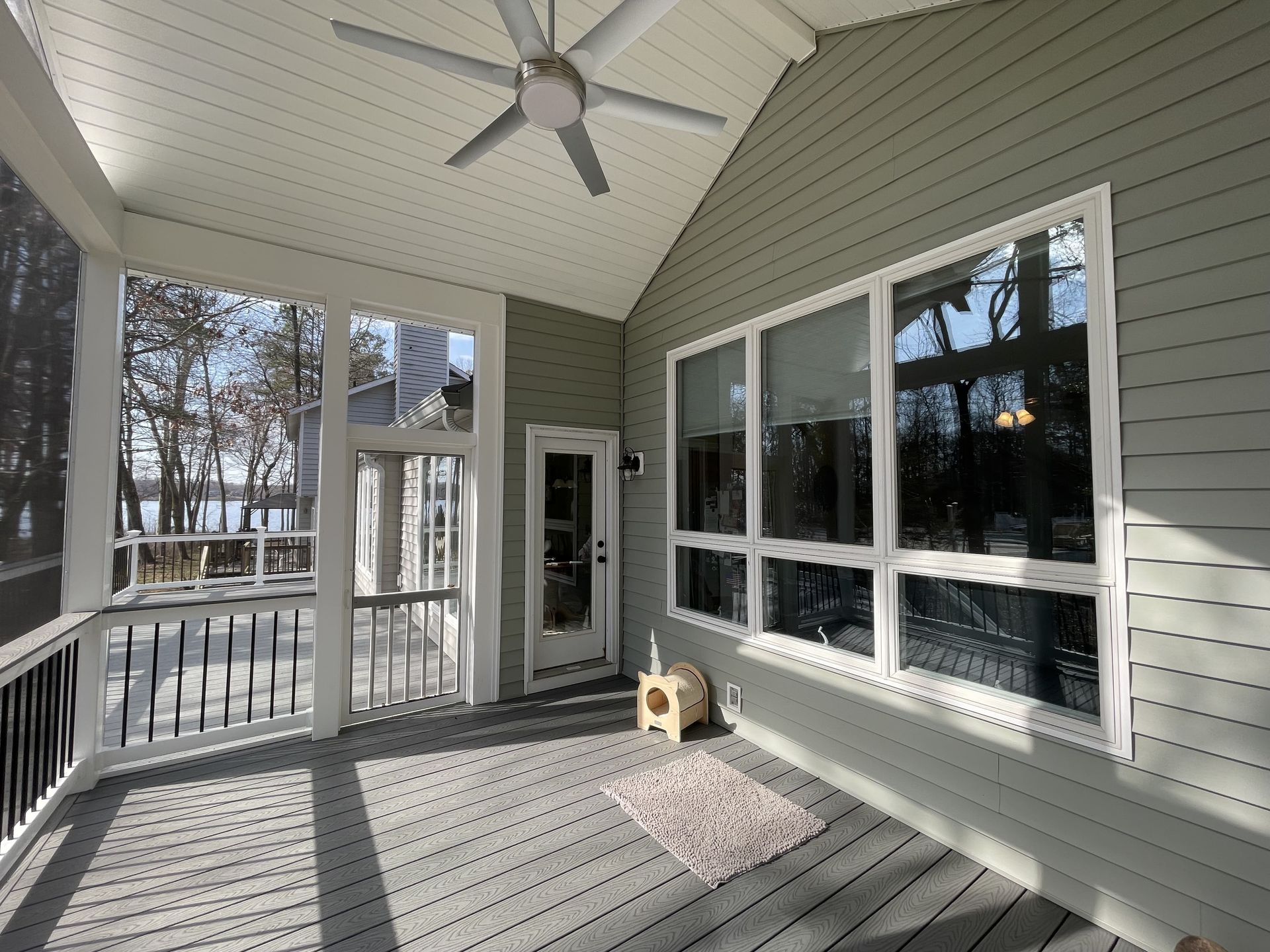 A screened in porch with a ceiling fan and lots of windows