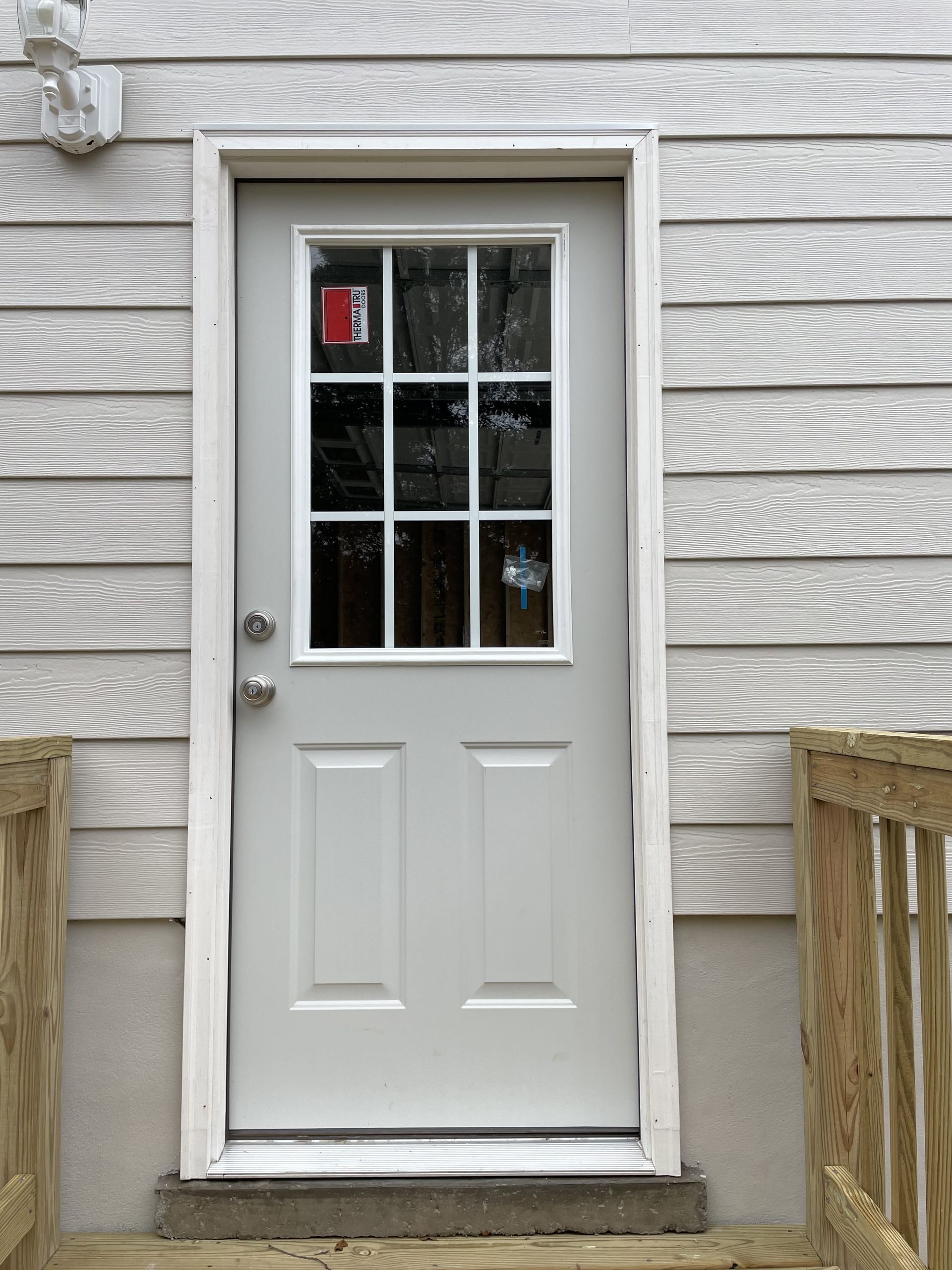 A white door with a glass window is on the side of a house.