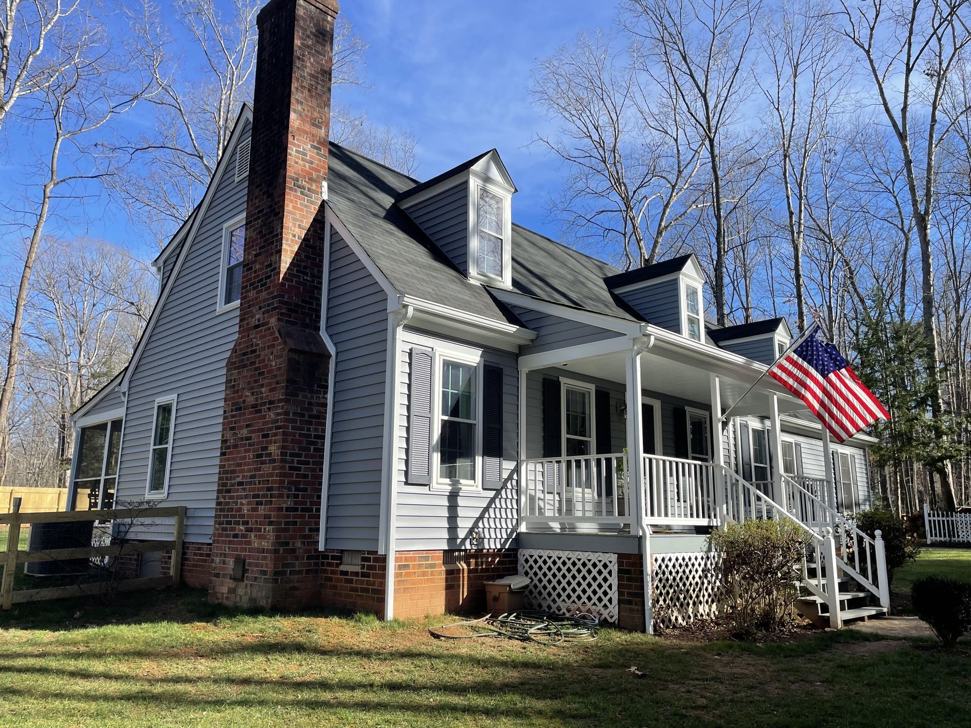 A large white house with a large porch and an american flag in front of it.