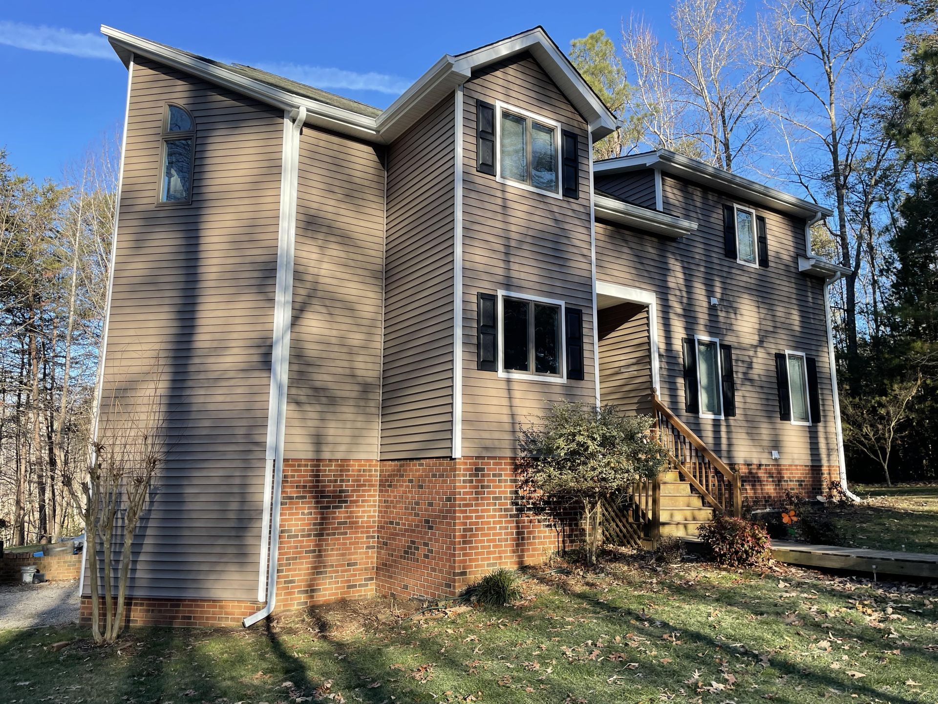 A large house with a lot of windows and stairs is sitting on top of a lush green field.