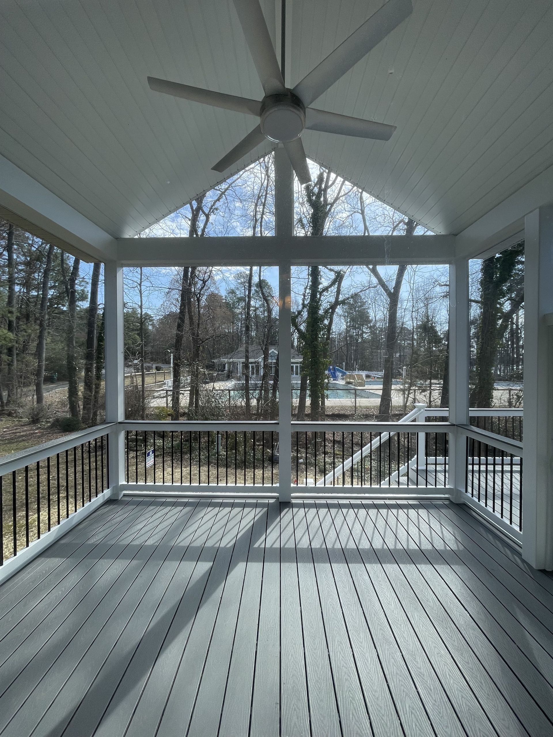 A screened in porch with a ceiling fan