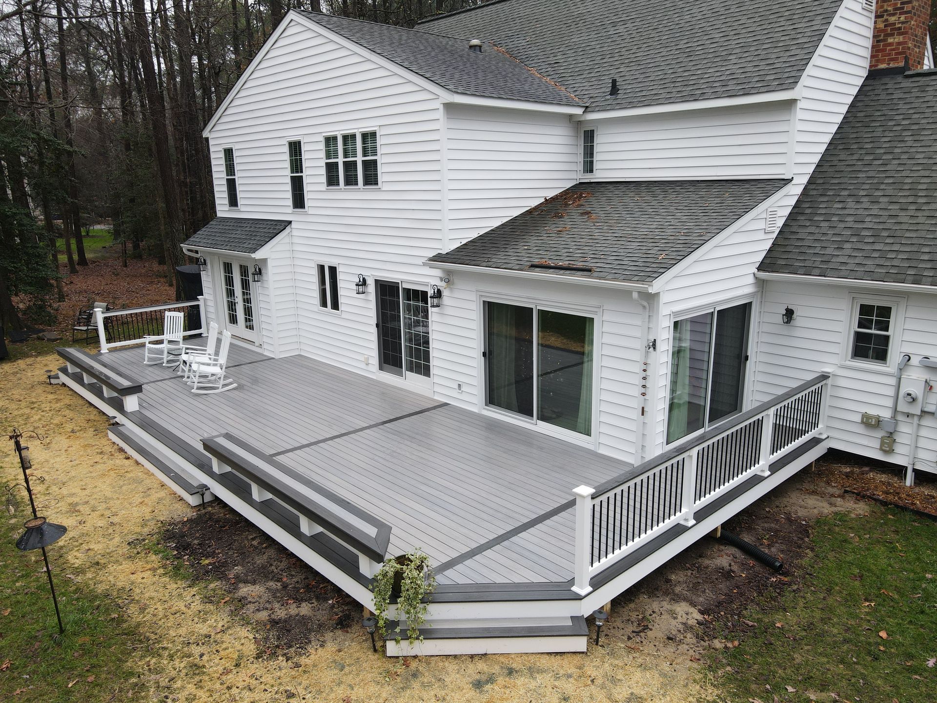 An aerial view of a large white house with a large deck.