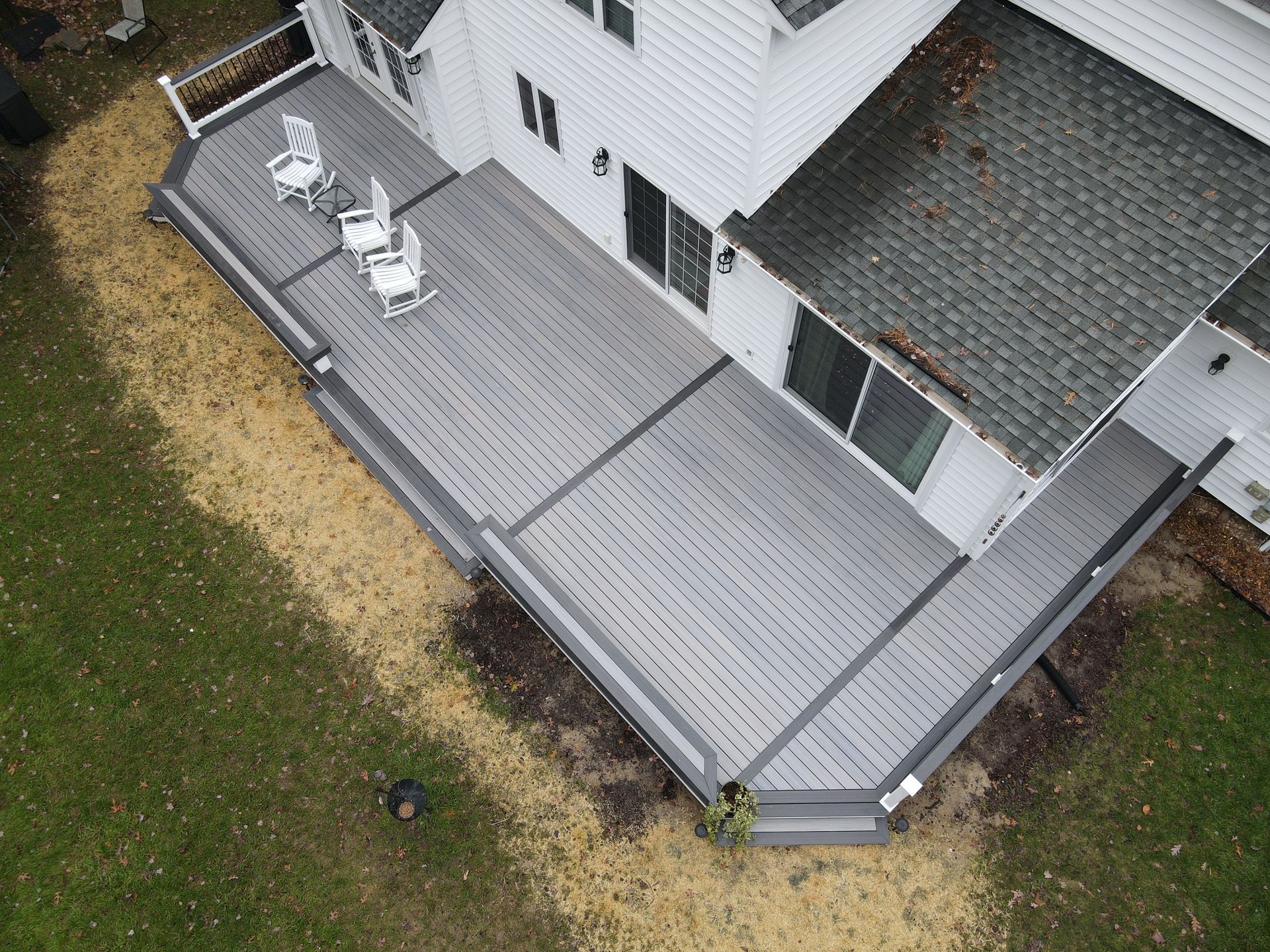An aerial view of a deck with chairs on it in front of a house.