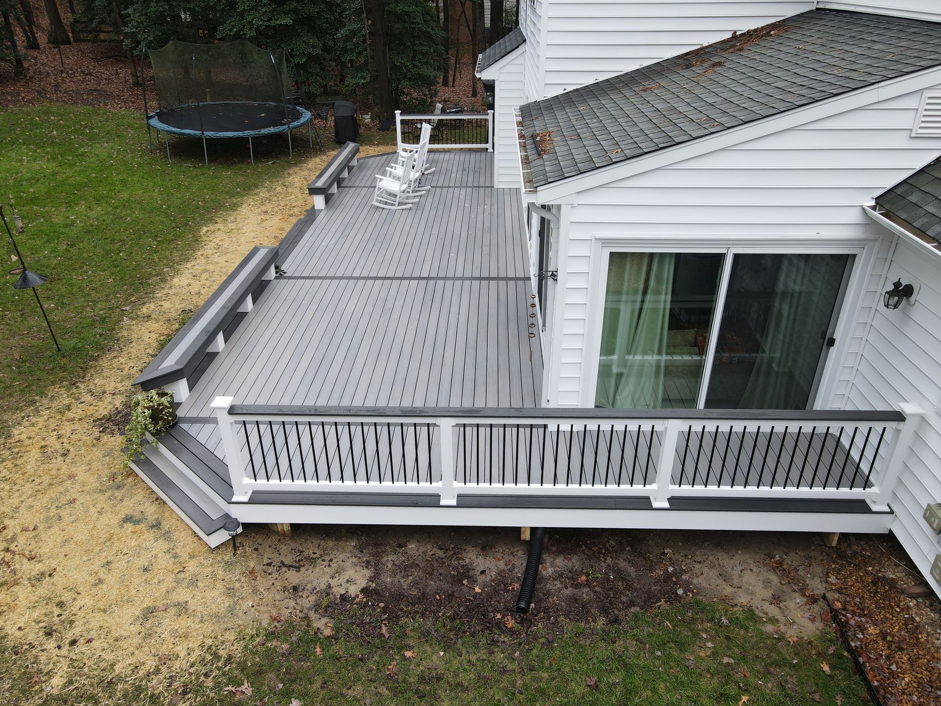 An aerial view of a deck with a trampoline in the backyard of a house.