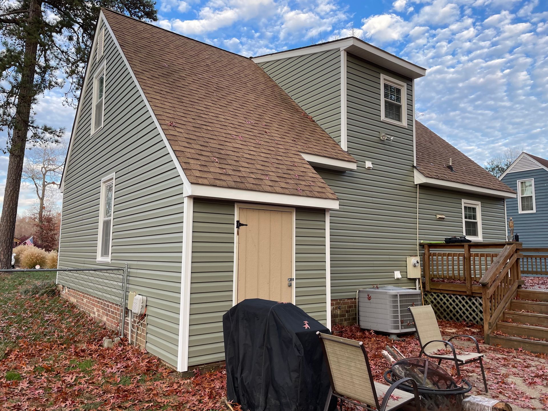 A green house with a brown roof and a fire pit in front of it.