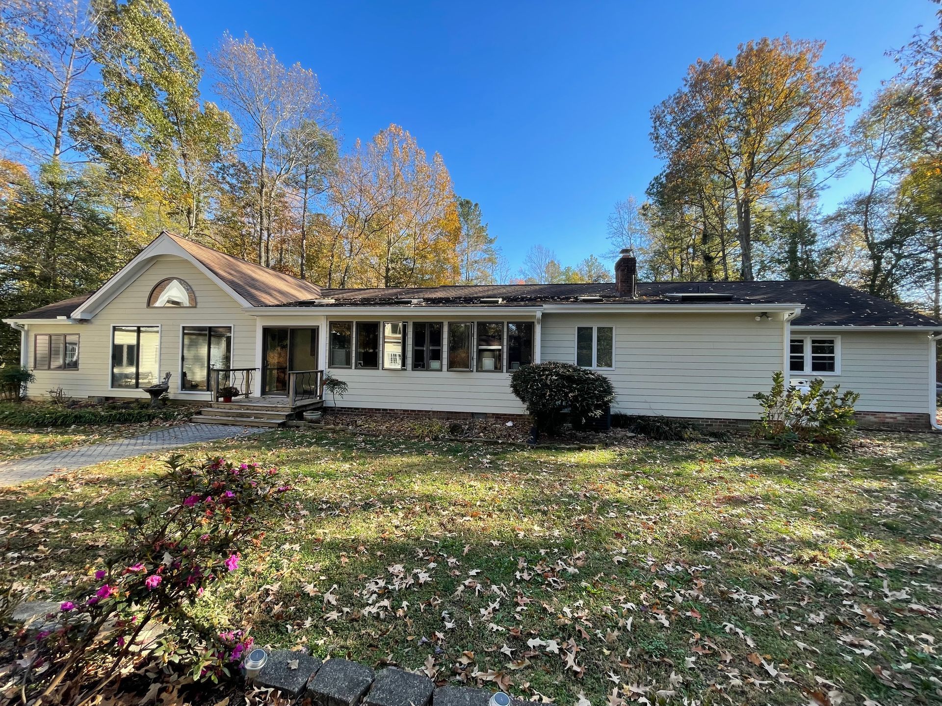 A large white house with a lot of windows is surrounded by trees on a sunny day.