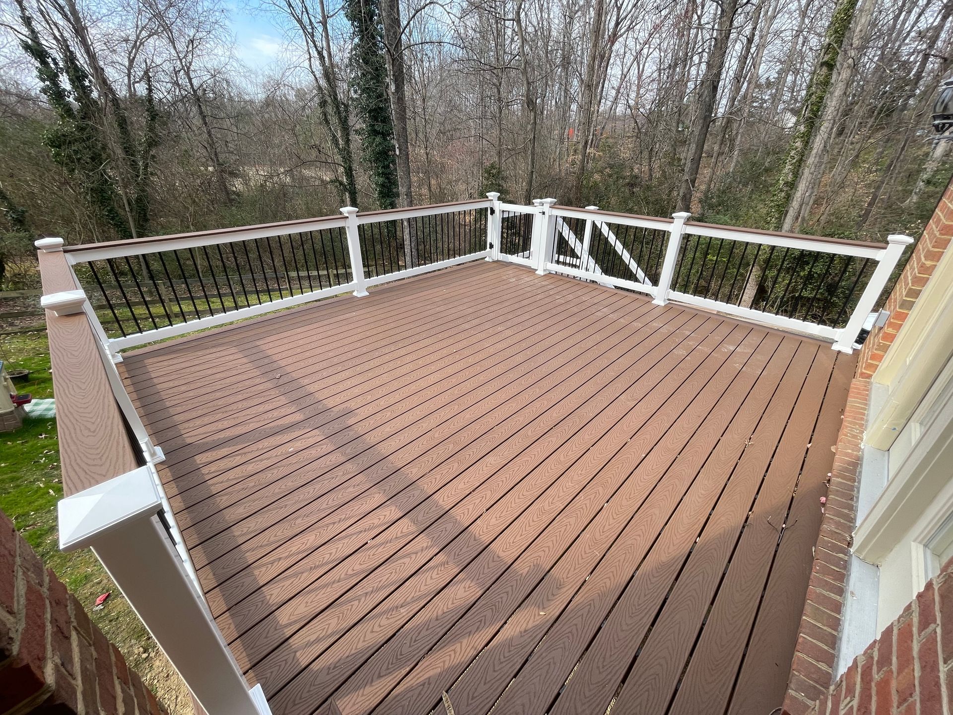 A wooden deck with a white railing and trees in the background.