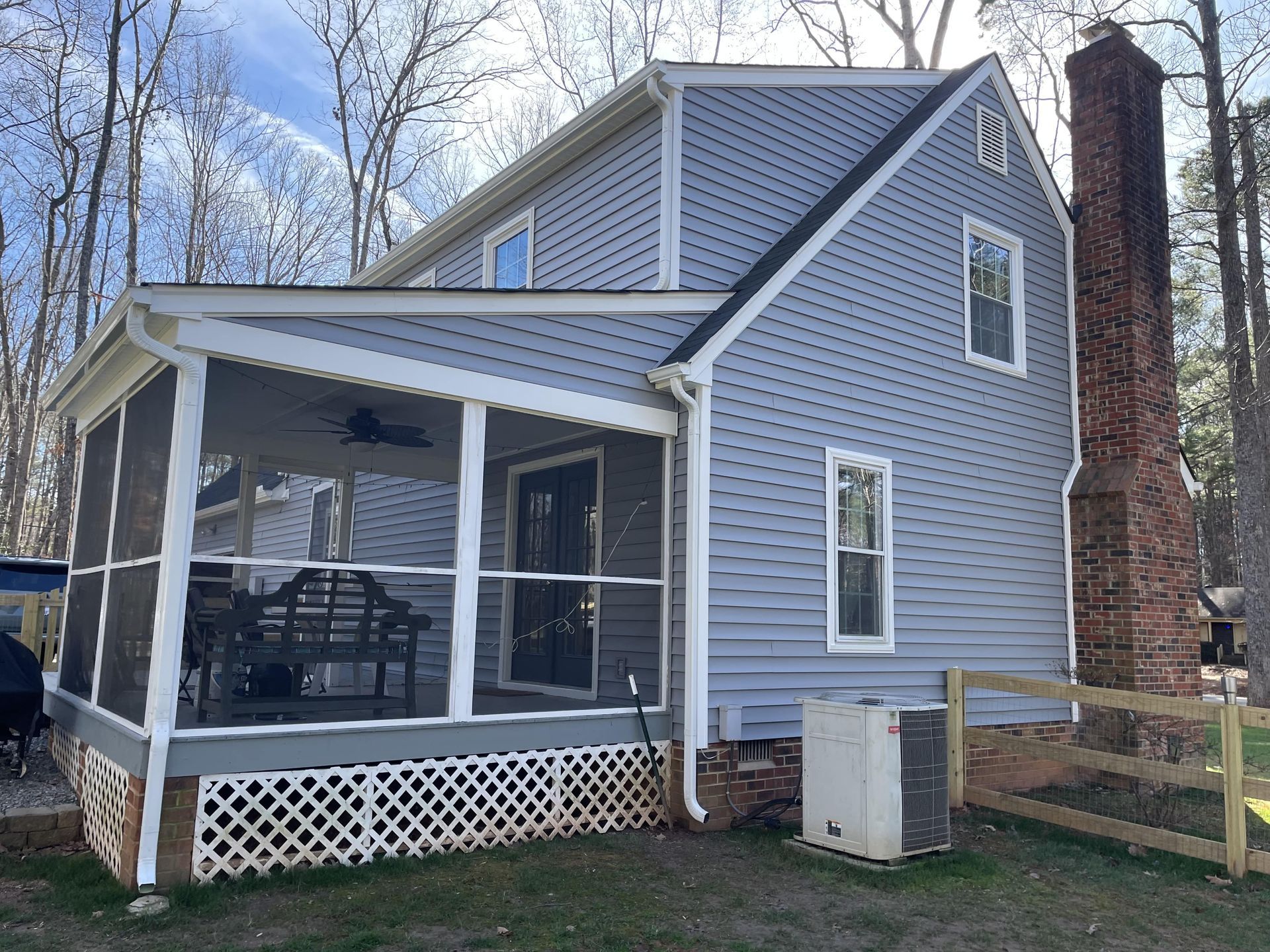 A house with a screened in porch and a chimney.