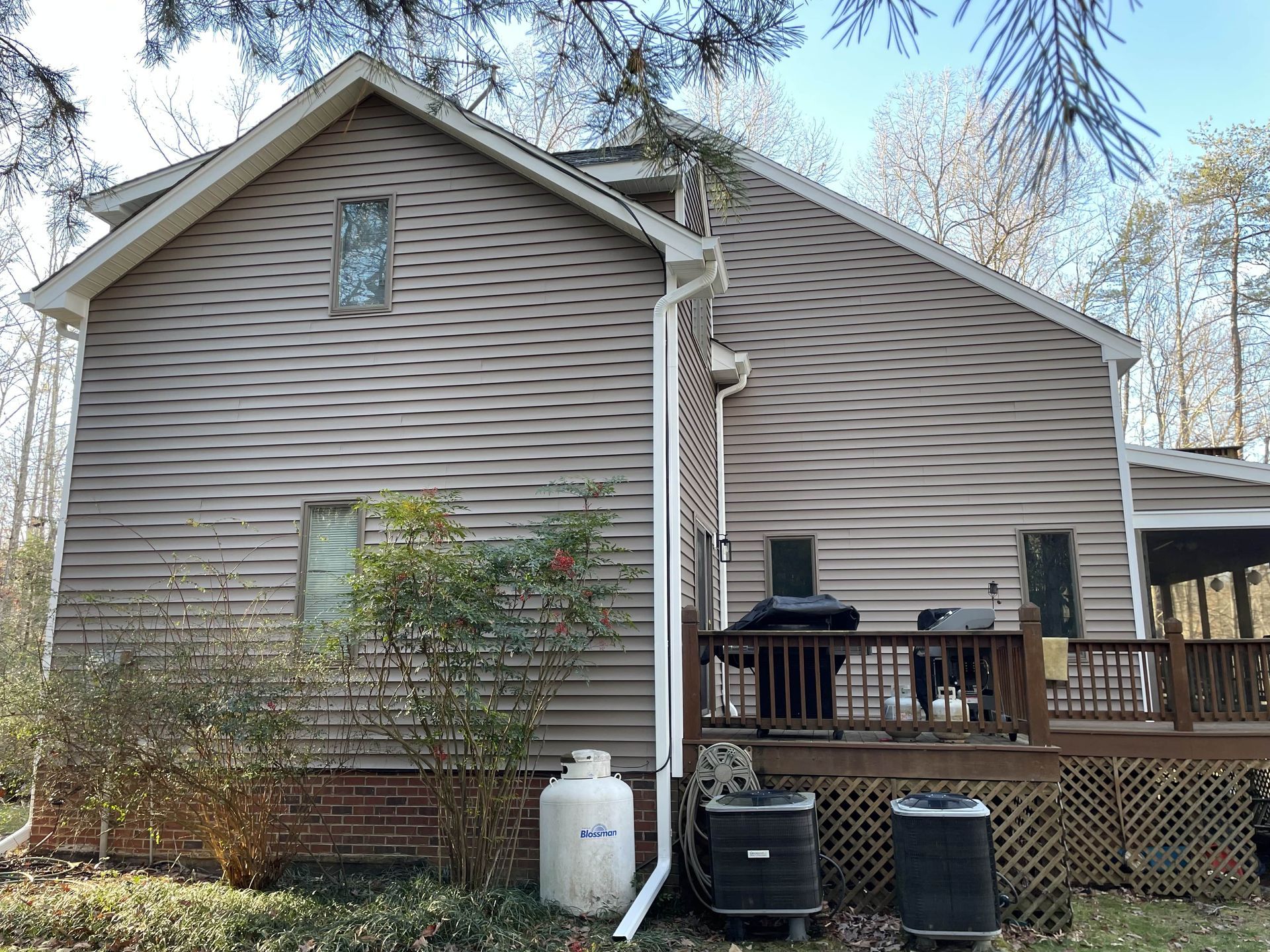 The back of a house with a deck and a propane tank.