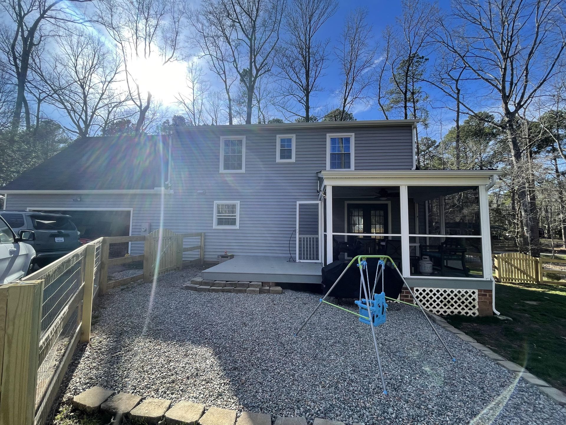 A house with a screened in porch and a gravel driveway.