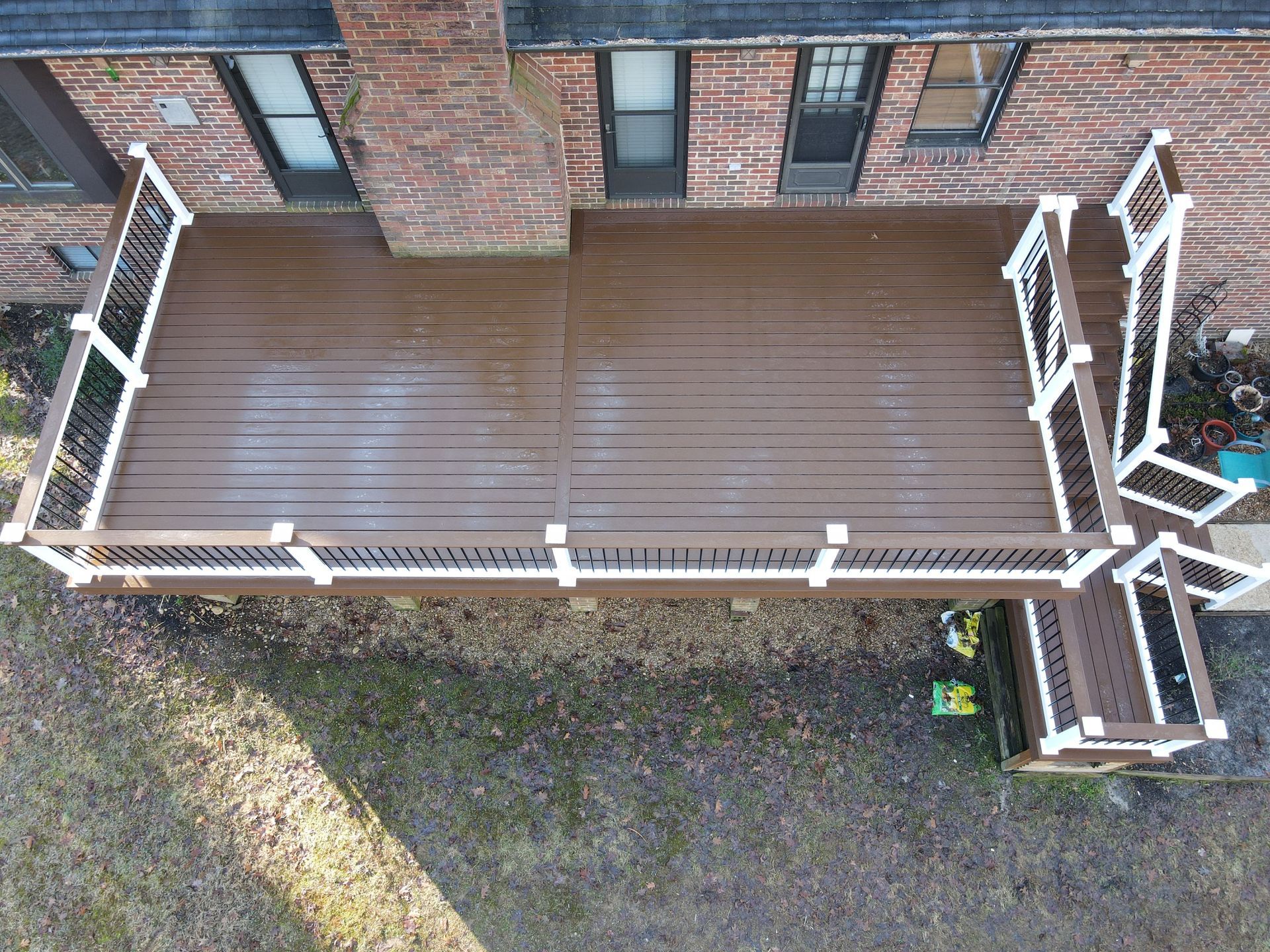 An aerial view of a wooden deck in front of a brick house.