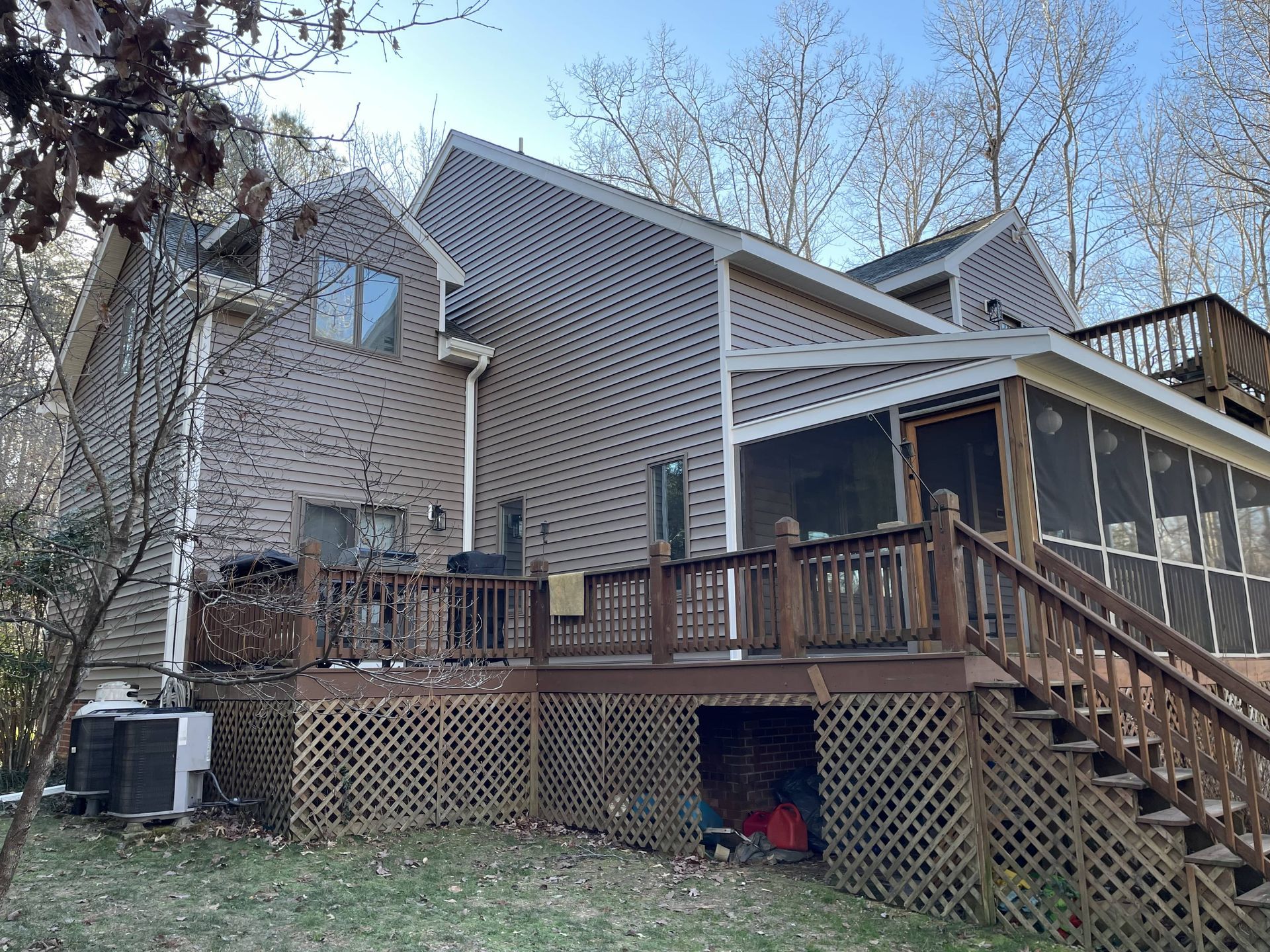 A large brick house with a screened in porch and stairs.