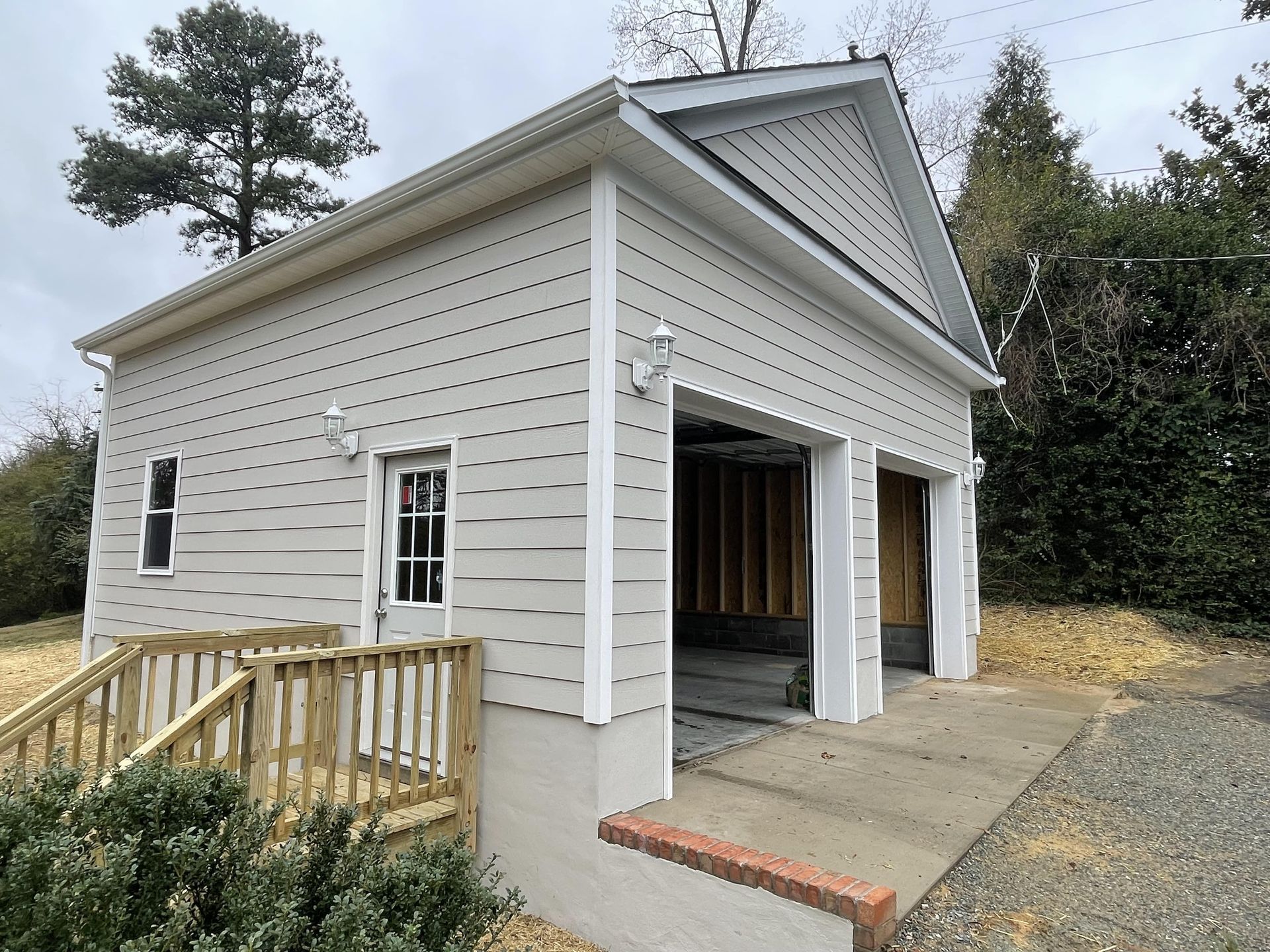 A small white house with a garage and a wooden deck