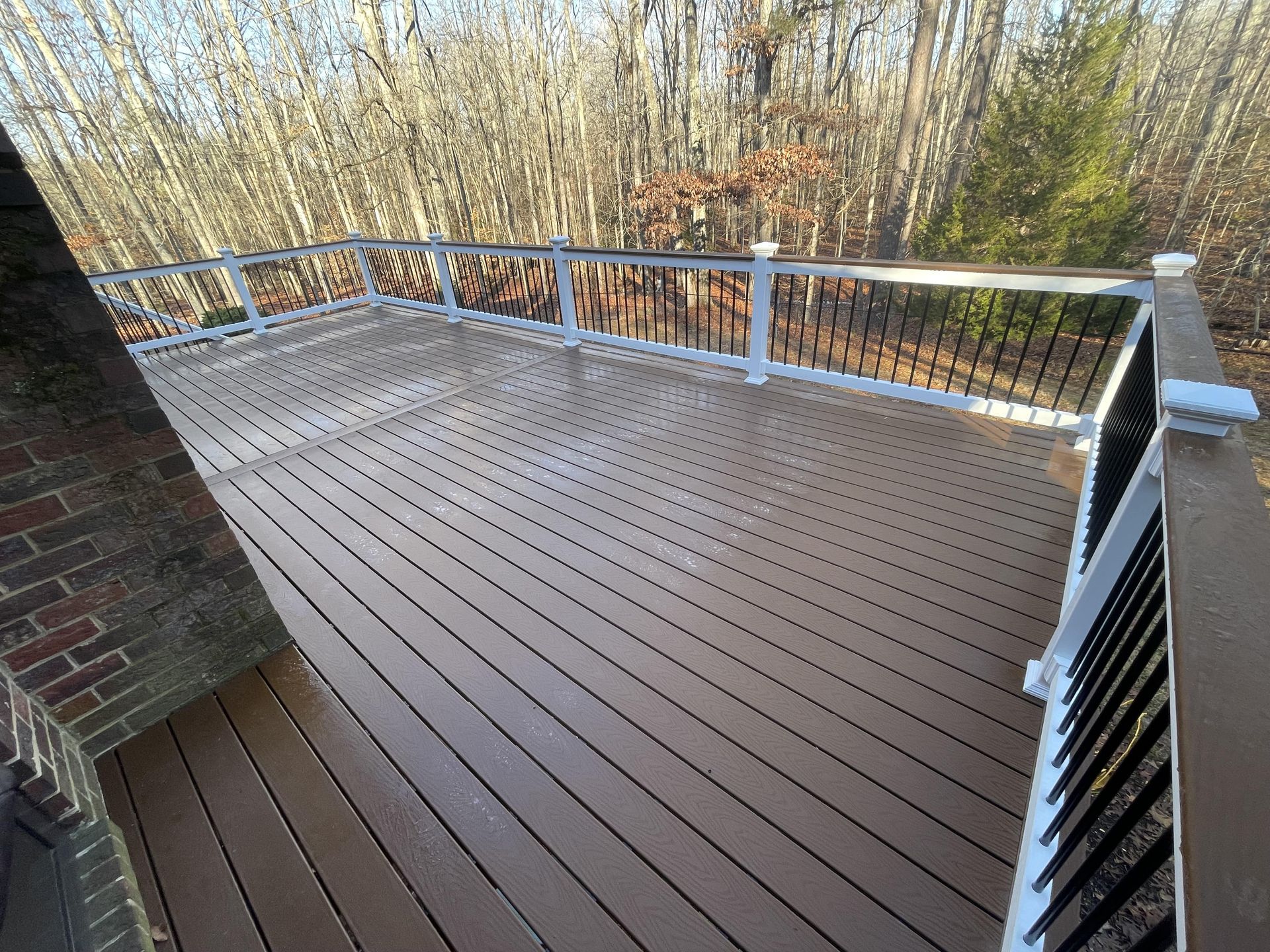 A wooden deck with a white railing and trees in the background.