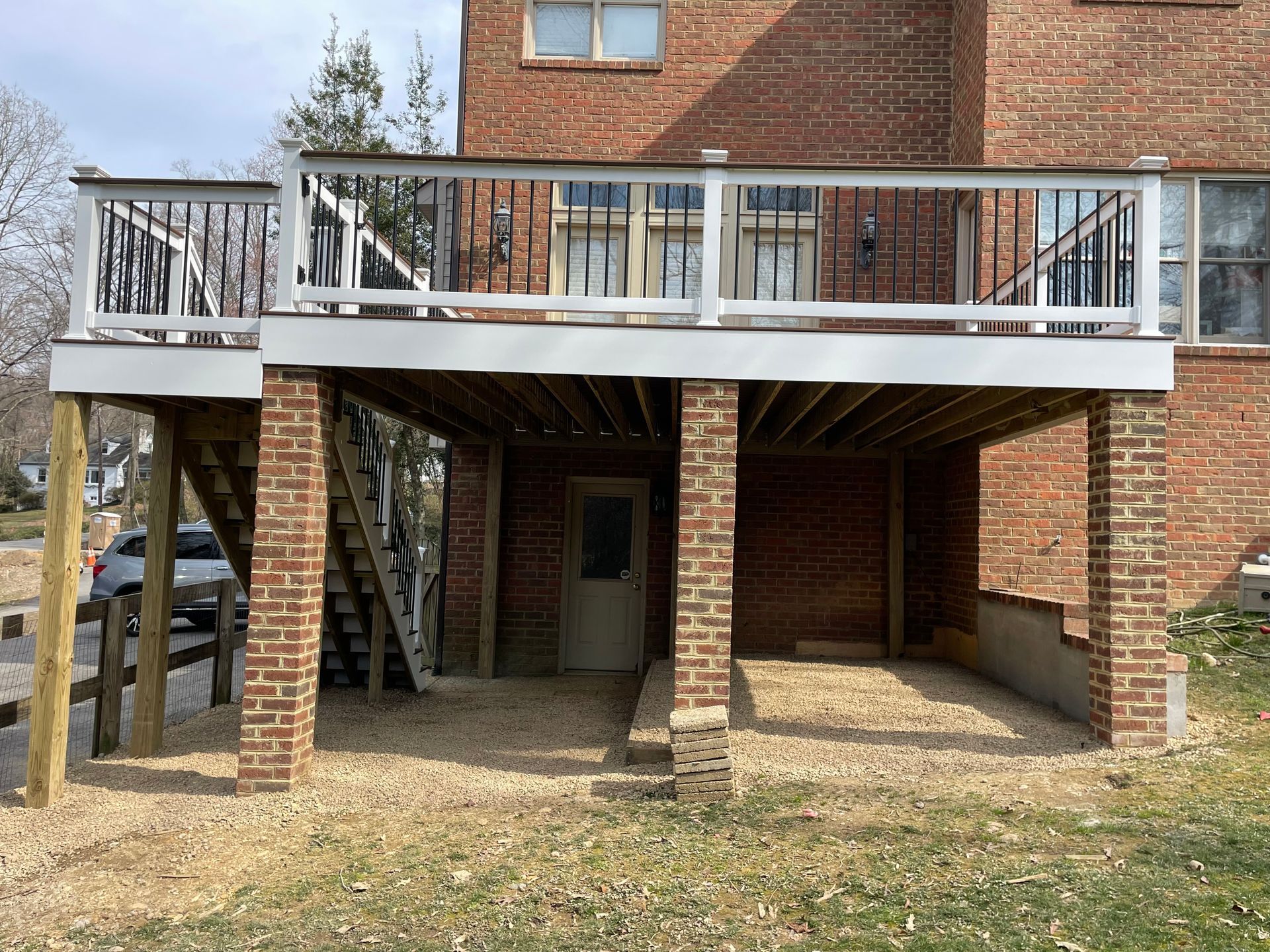 A brick house with a deck and stairs underneath it.