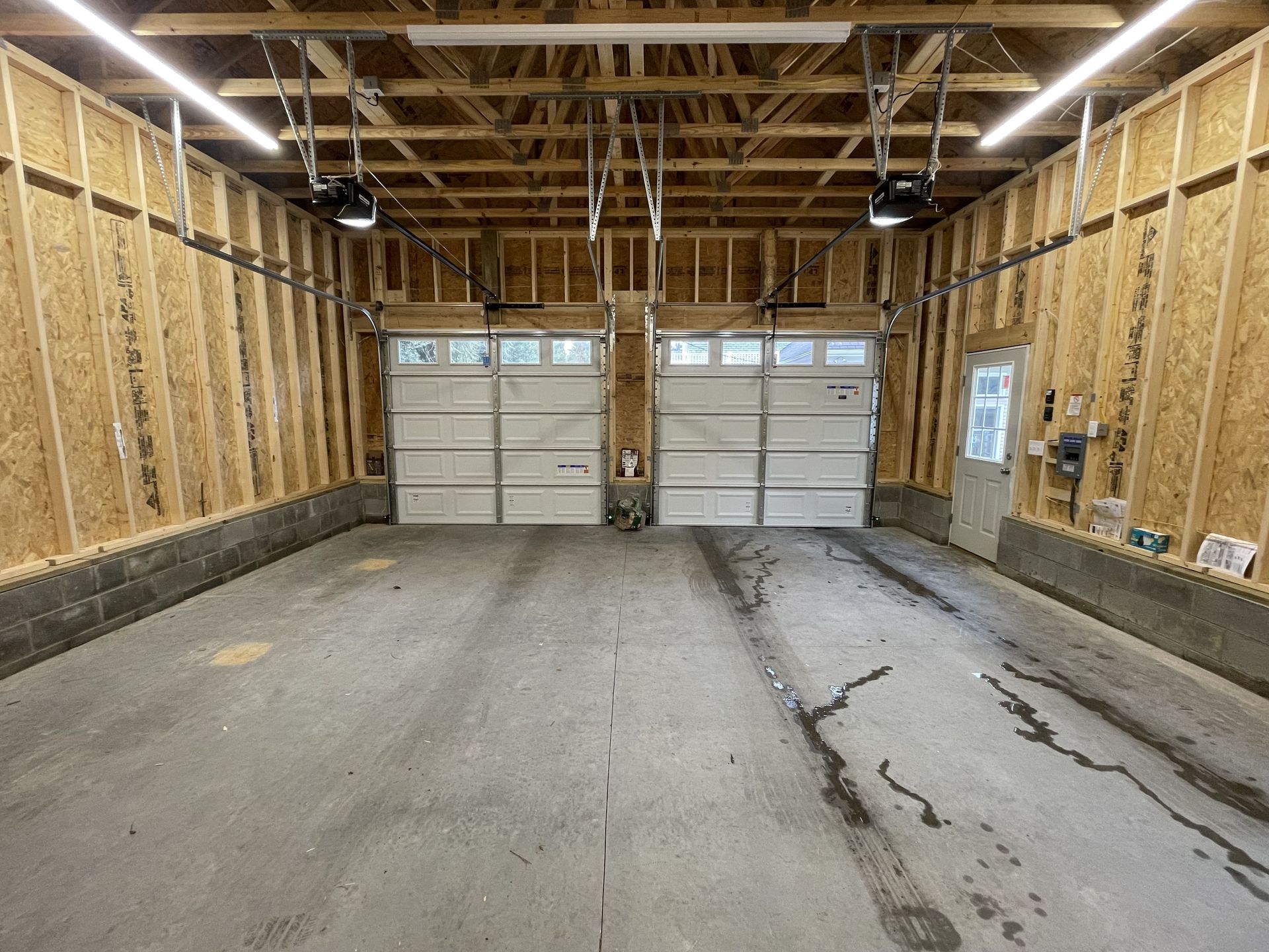 A garage with two garage doors and a concrete floor.