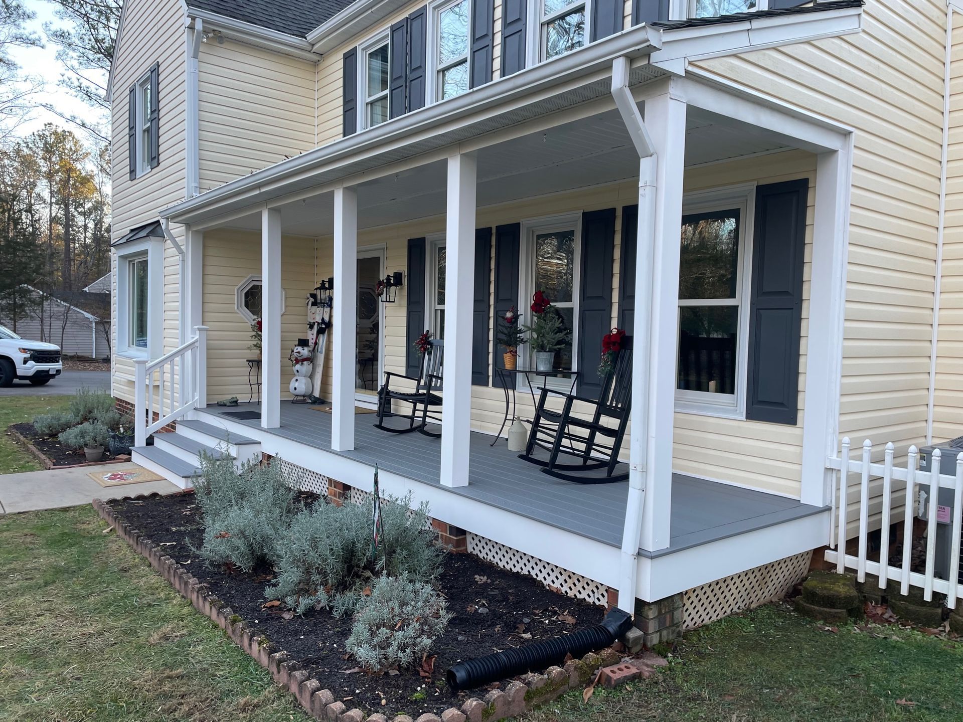 A yellow house with a porch and rocking chairs on it.