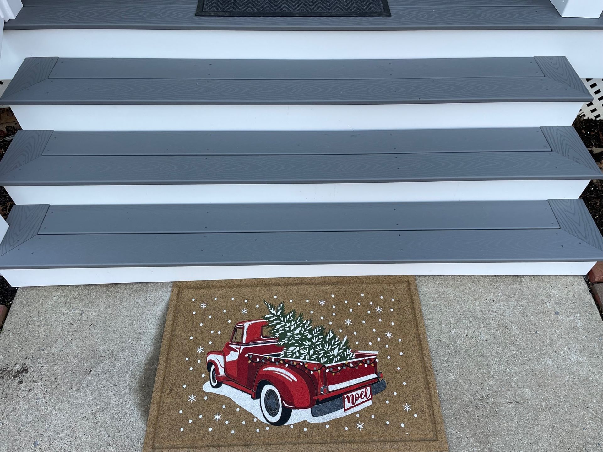 A red truck is carrying a christmas tree in the back of it.