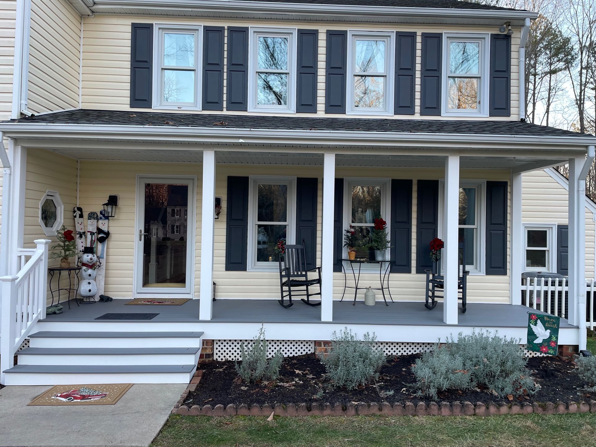 A yellow house with black shutters and a porch