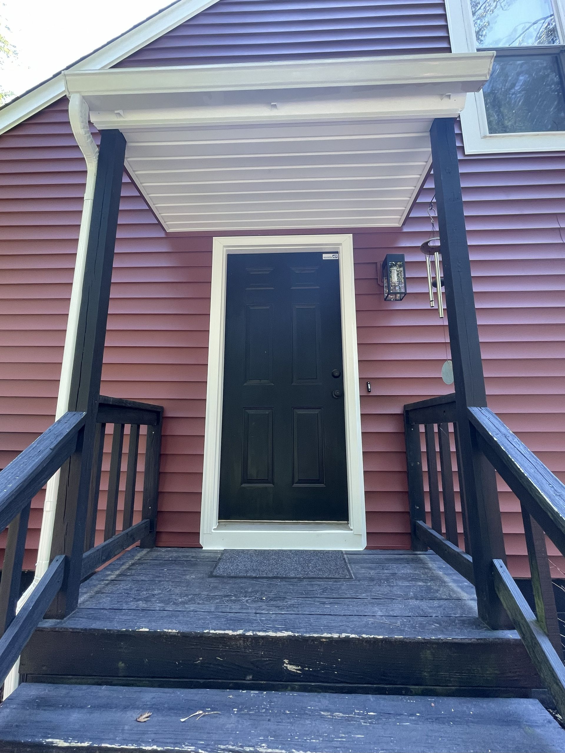Dark front door under a small porch with steps. The house is red.