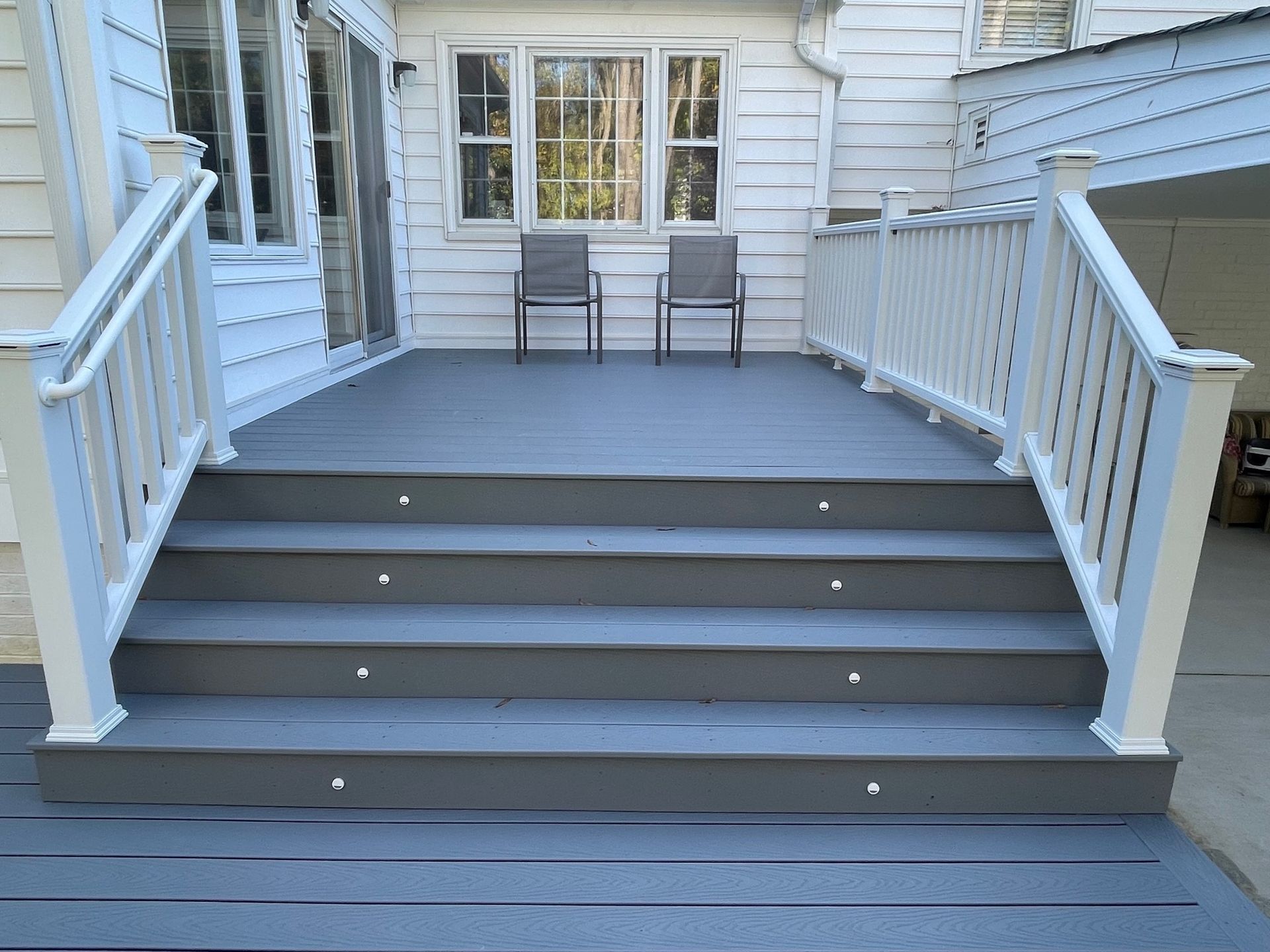 A deck with stairs leading up to it and two chairs on it.