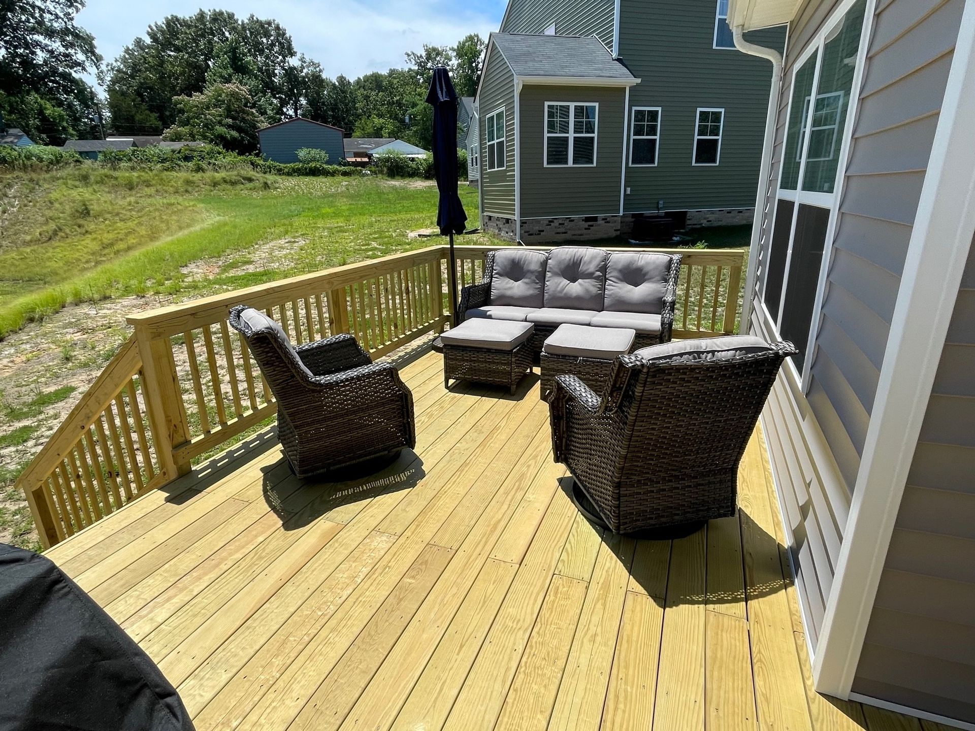 A wooden deck with a couch , chairs , and umbrella.