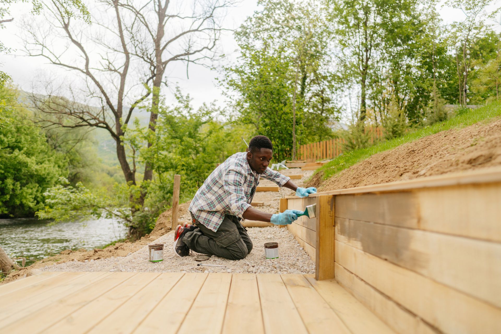 A residential deck builder painting a wooden decking next to a river. A residential deck builder painting a wooden decking next to a river.