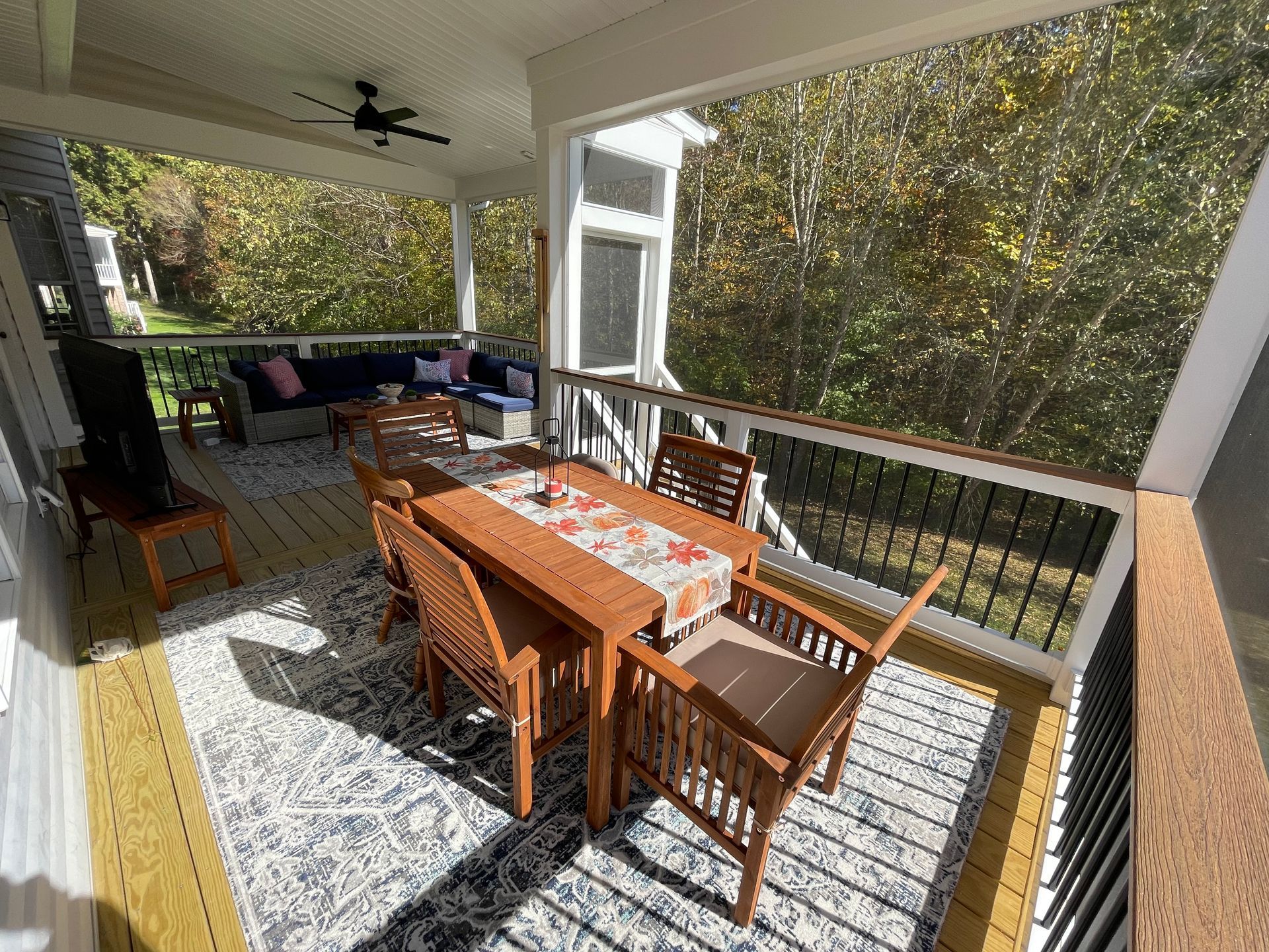 A screened in porch with a table and chairs on it.