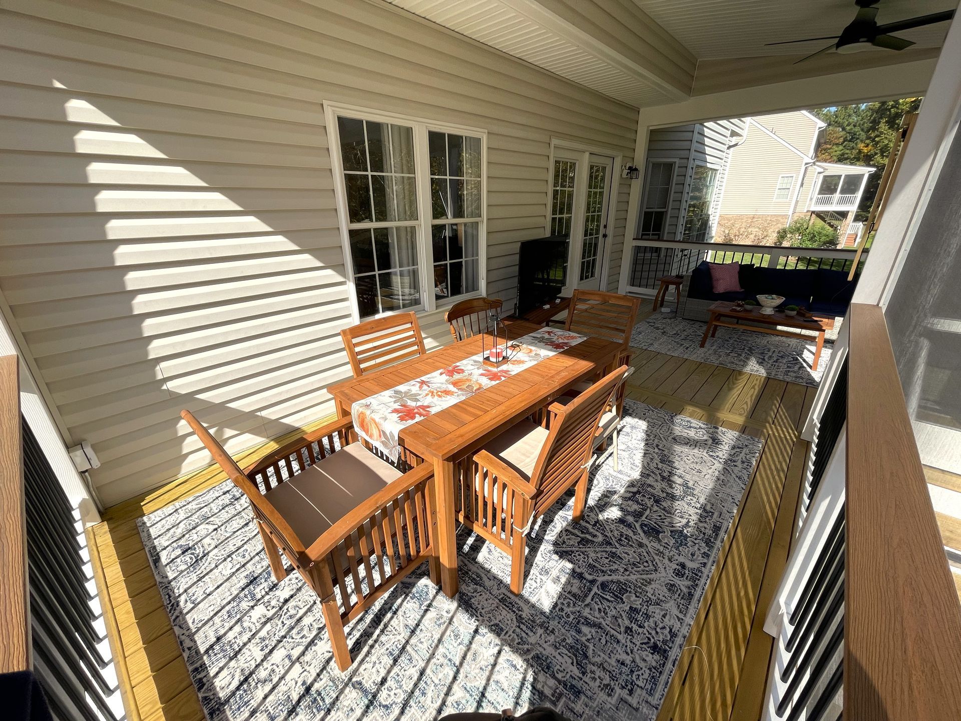 There is a table and chairs on the porch of a house.