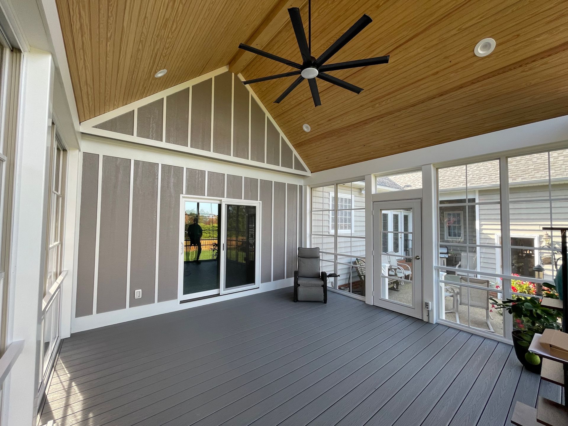 A screened in porch with a ceiling fan and sliding glass doors.
