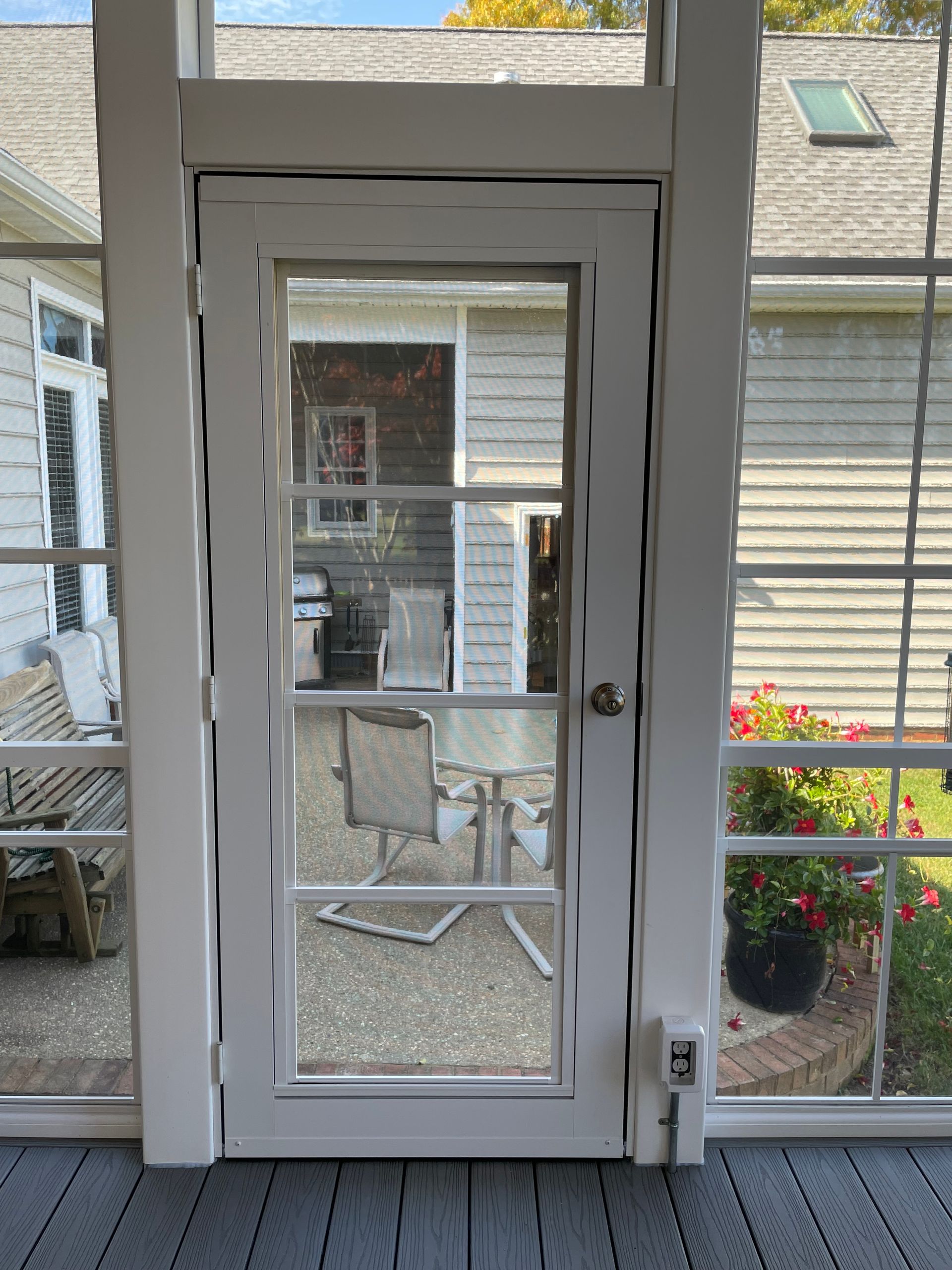 A screened in porch with a glass door leading to a patio.