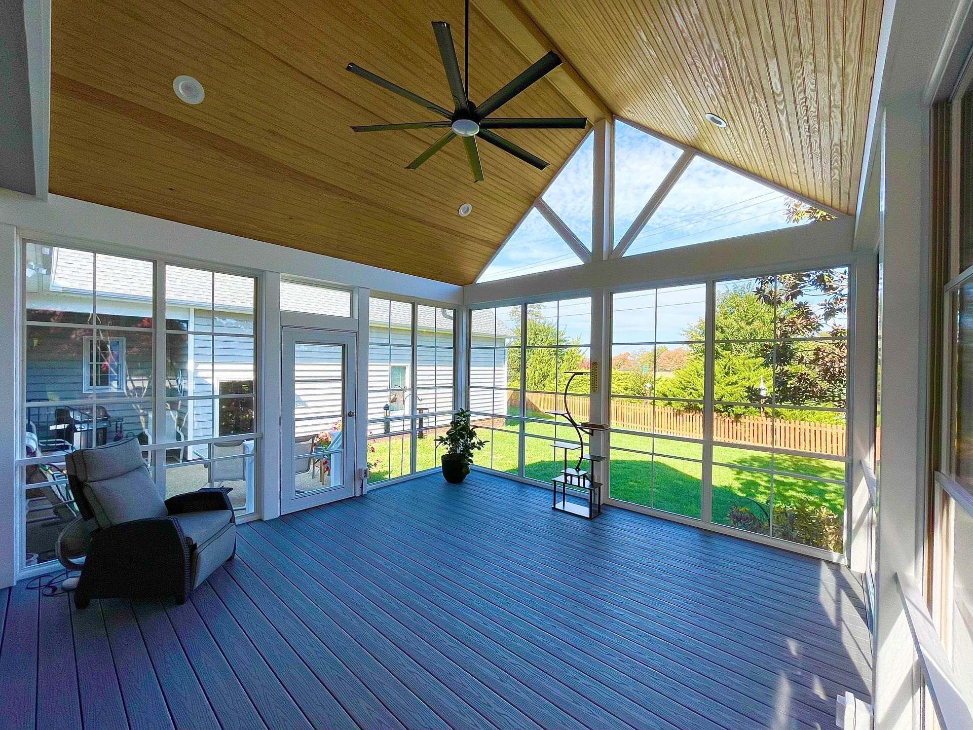 A screened in porch with a lot of windows and a ceiling fan.