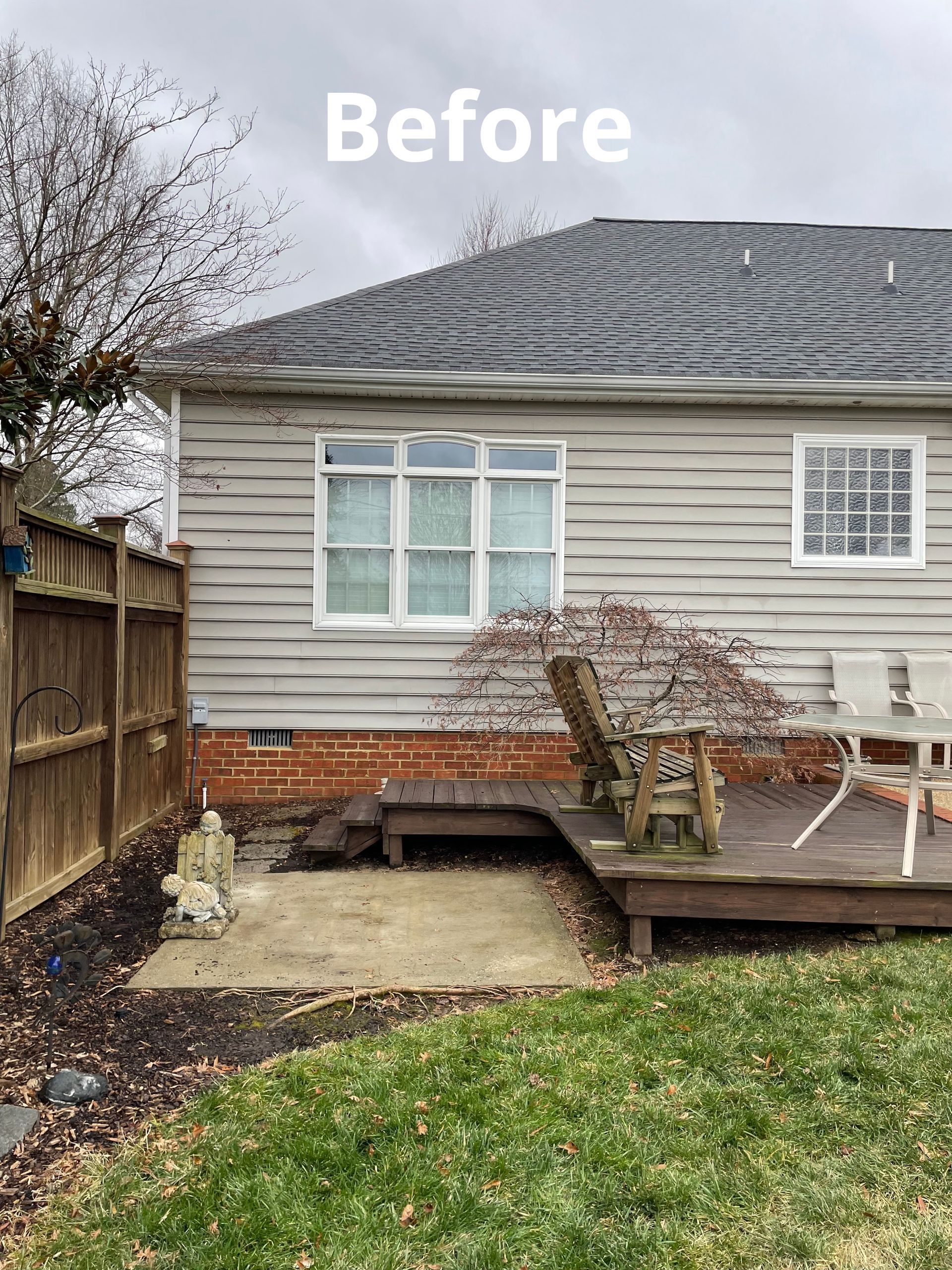 A before picture of a house with a deck and a fence.