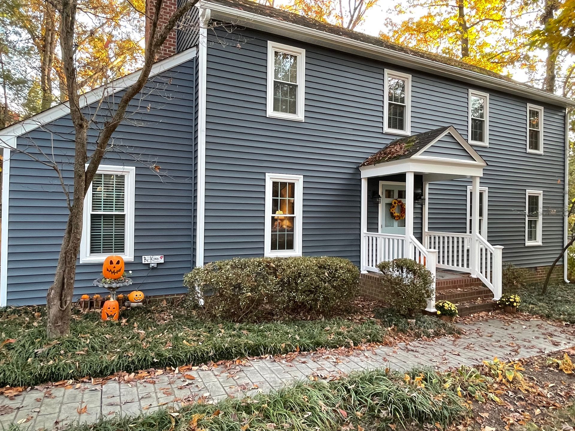 Two-story house with dark blue siding, white trim, and a small porch decorated for Halloween.