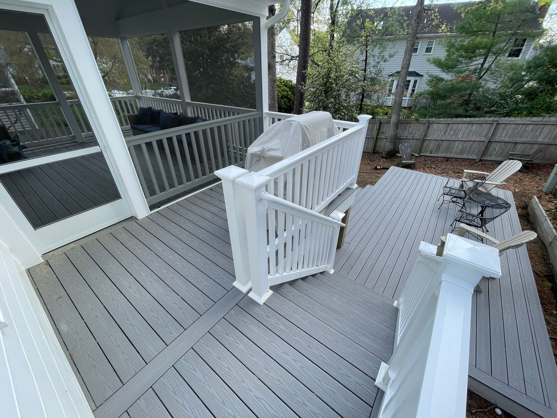 Gray composite deck with white railing; a screened porch is visible on the left.
