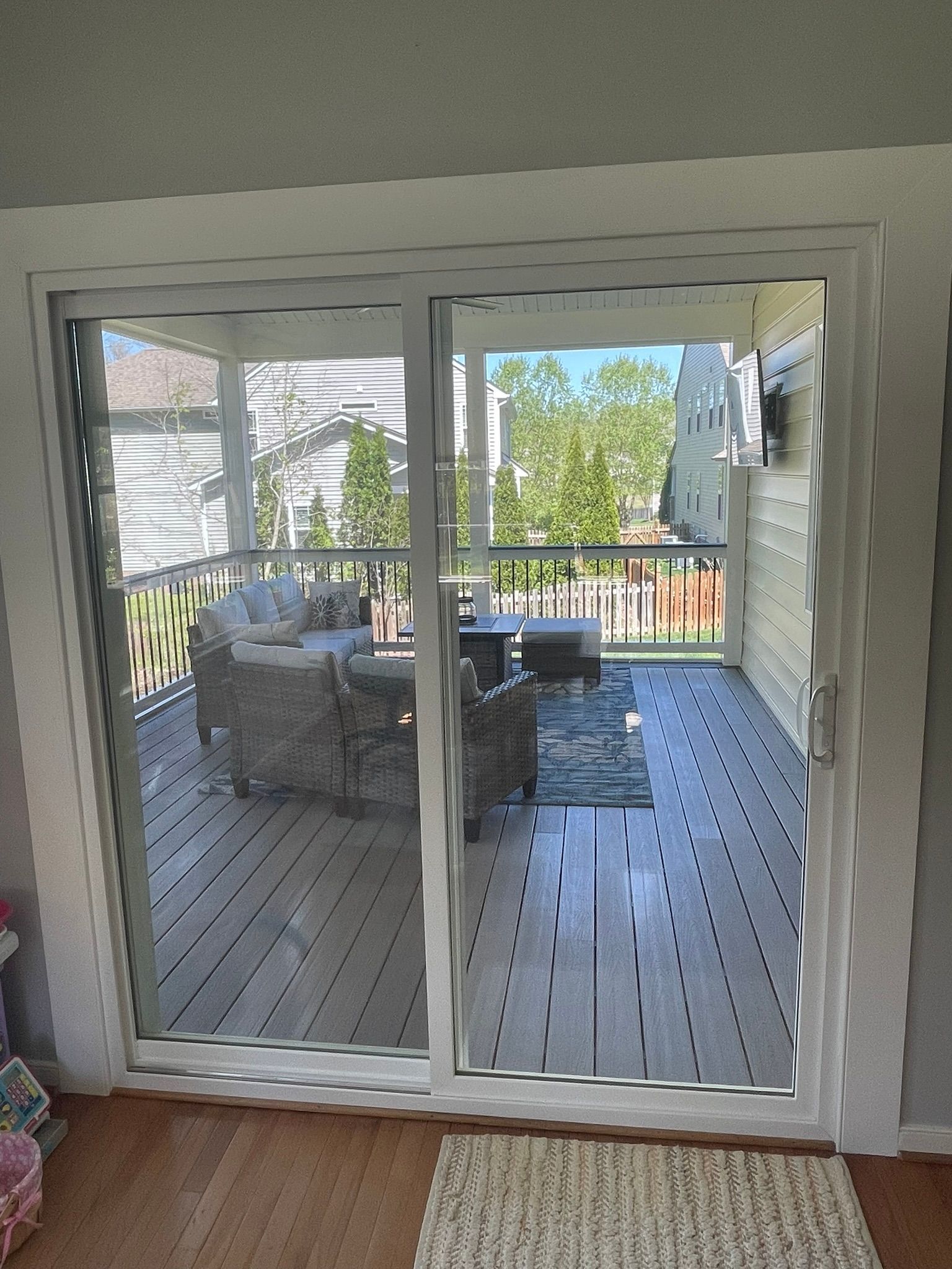 Sliding glass door opens to a deck with outdoor furniture. Sunlight streams through.