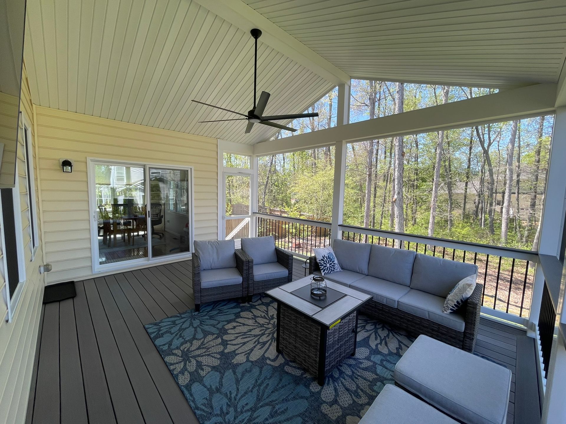 A screened in porch with a couch and a ceiling fan