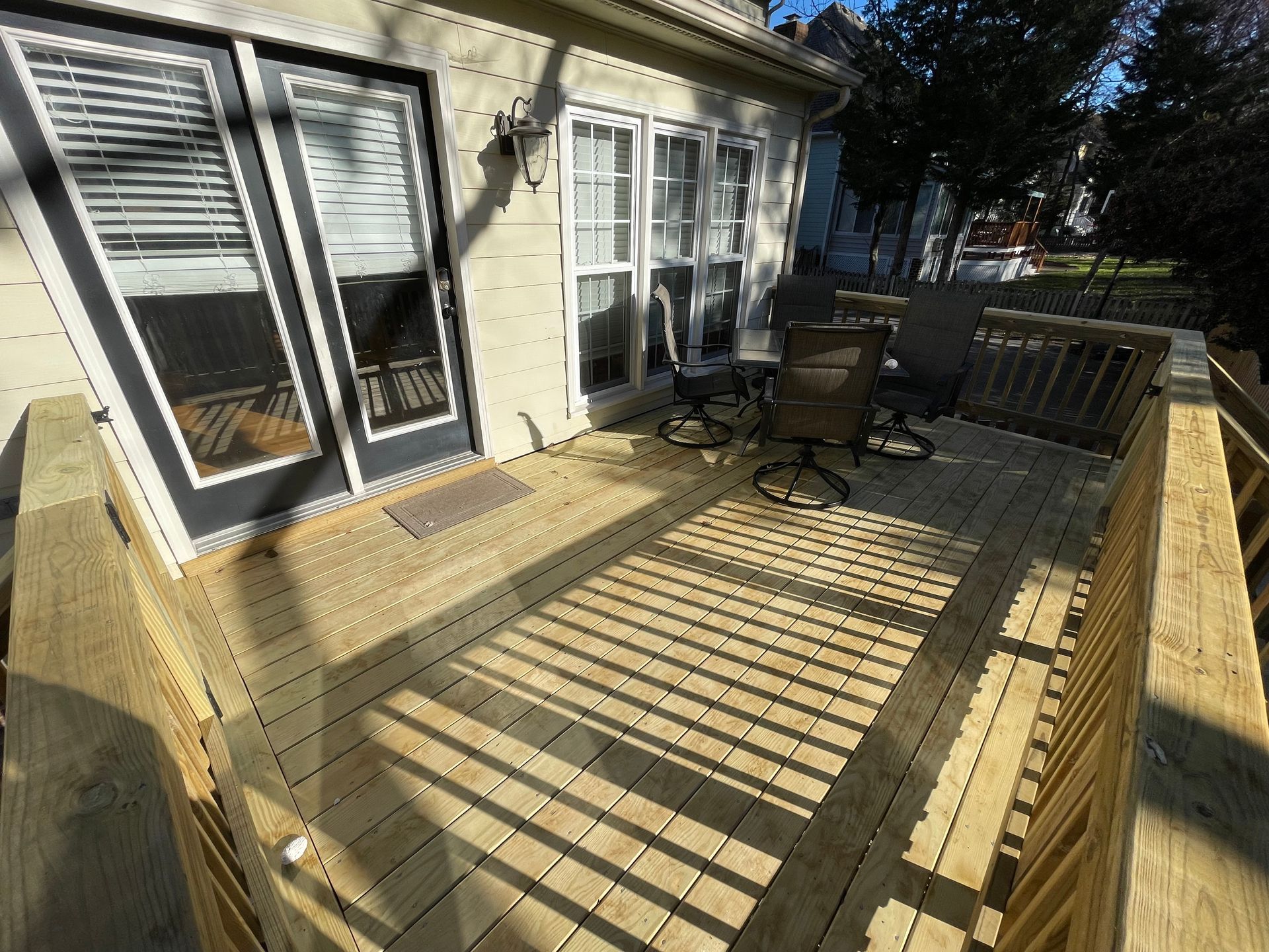 A wooden deck with chairs and a table in front of a house.