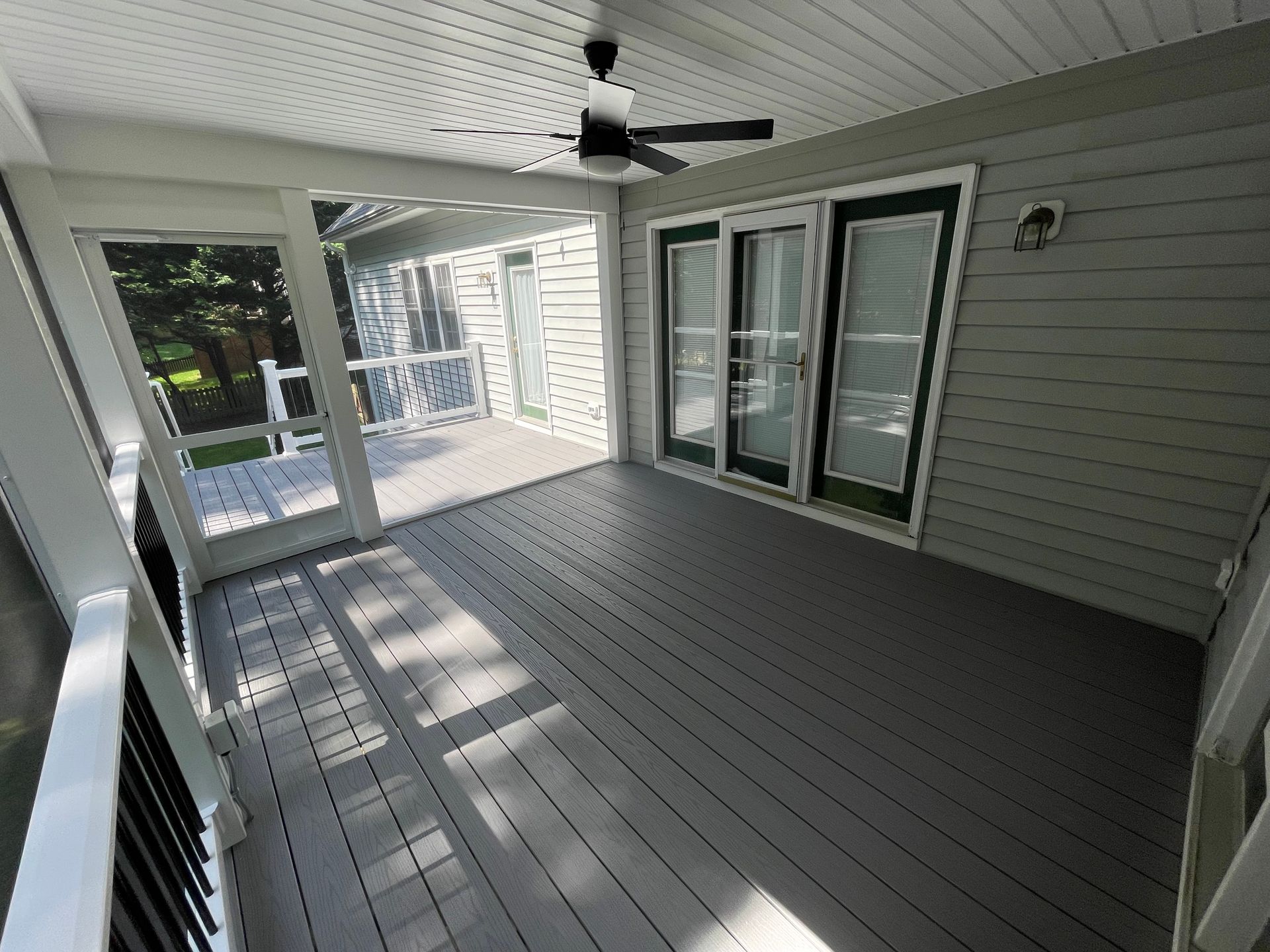Grey screened-in porch with deck and sliding glass doors. Ceiling fan.