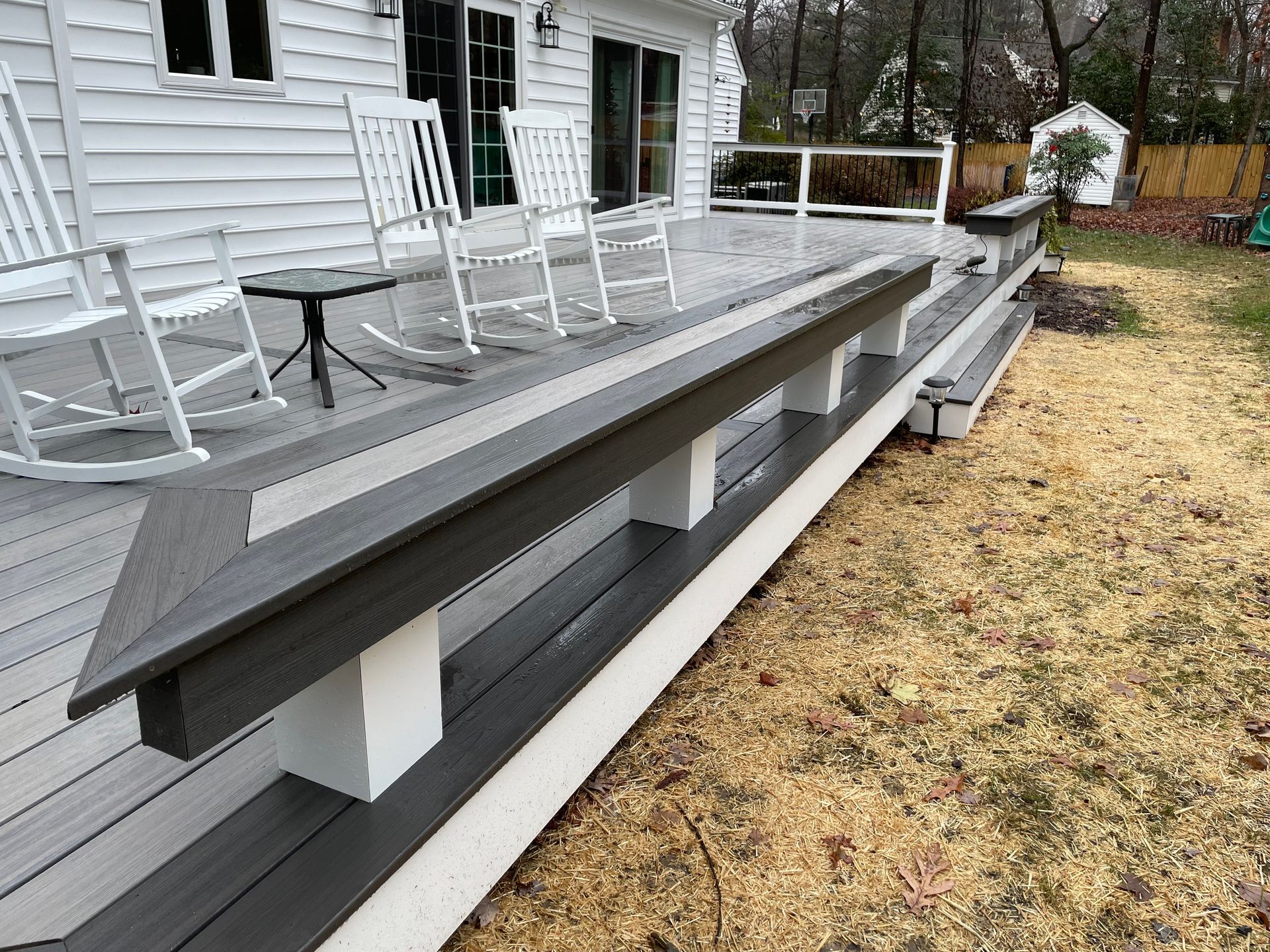 There are rocking chairs on the deck of a house.