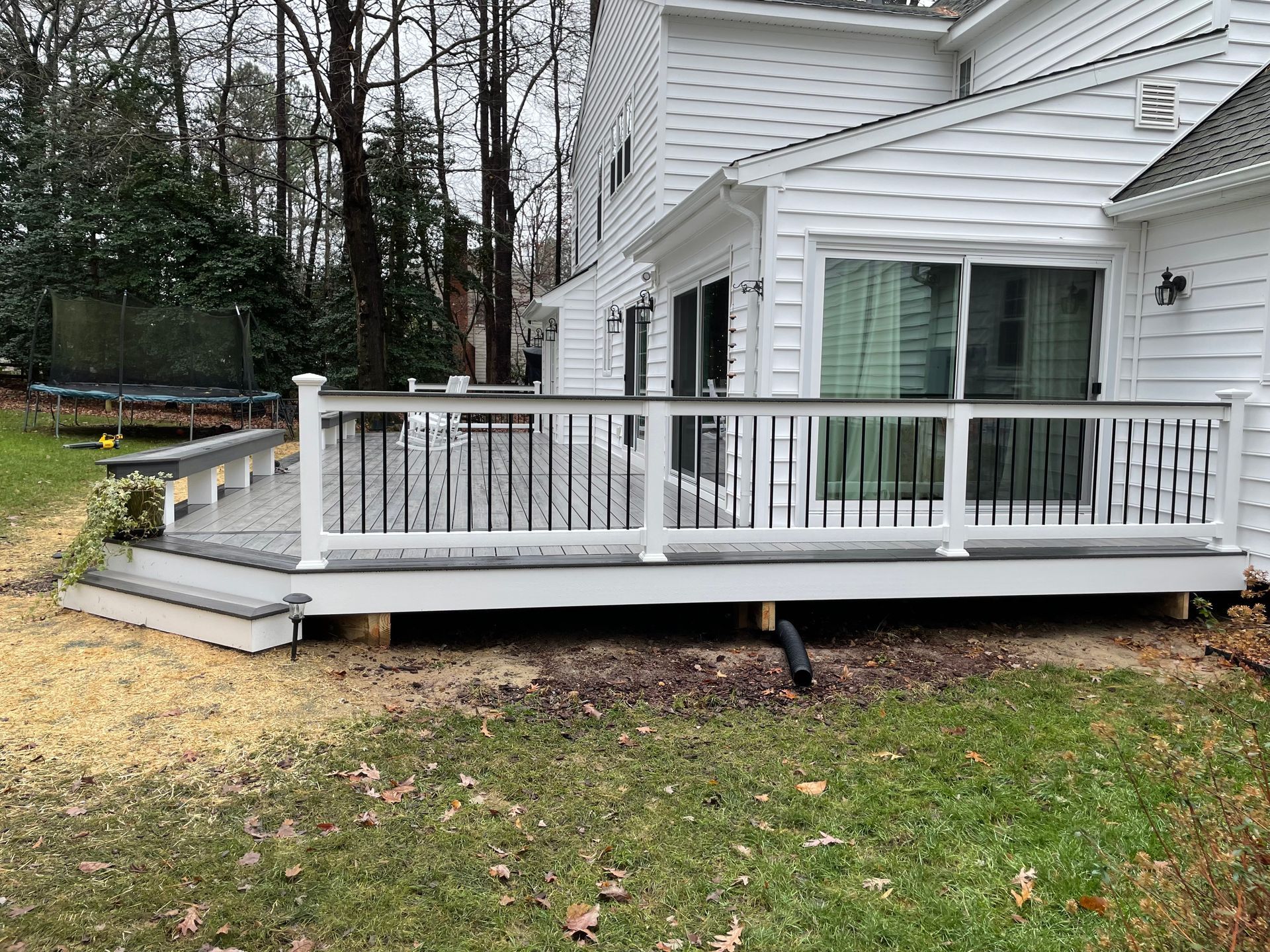 A white house with a large deck in front of it.