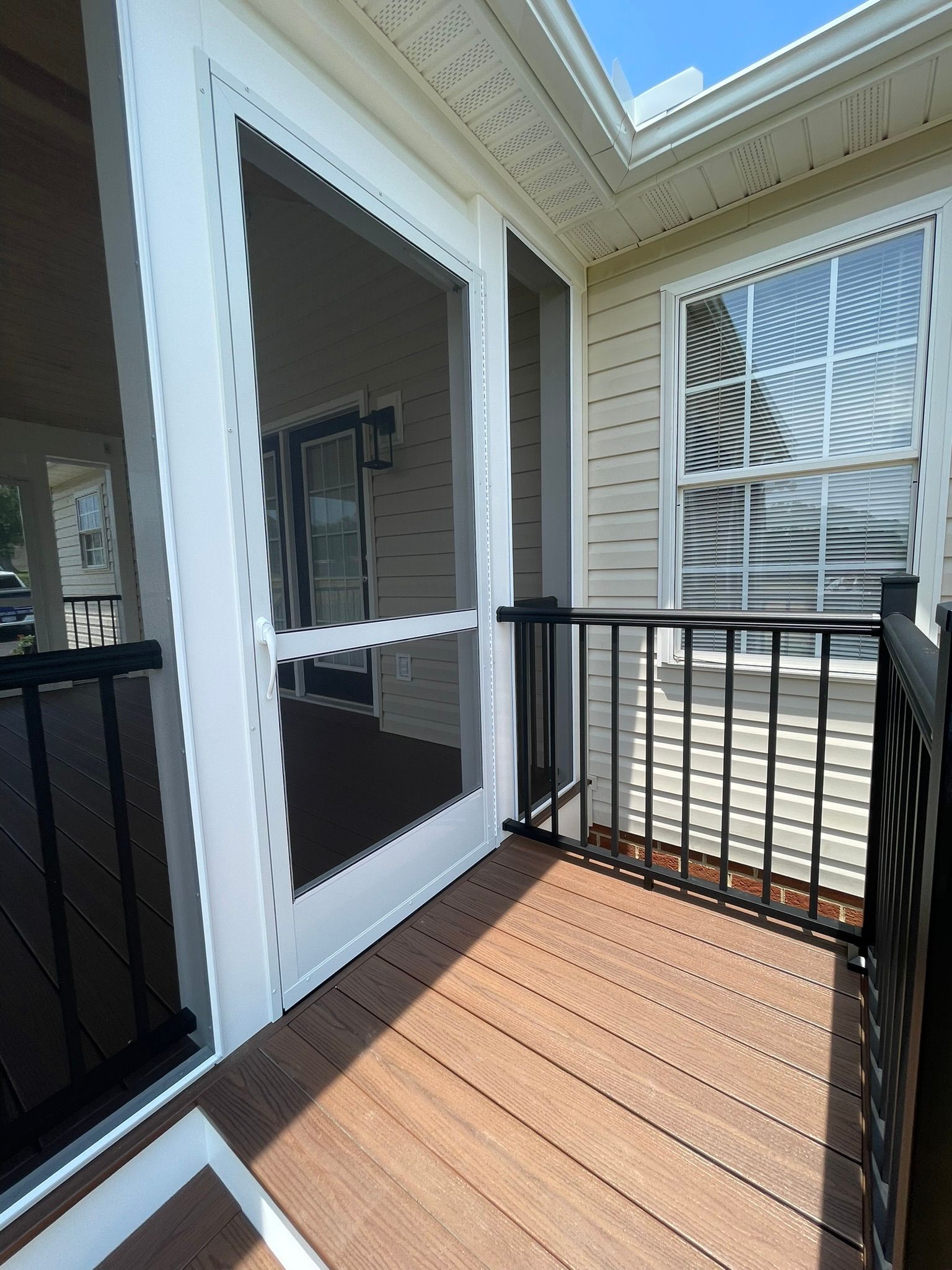 Screened porch with composite deck, black railing, and white trim. Window visible.