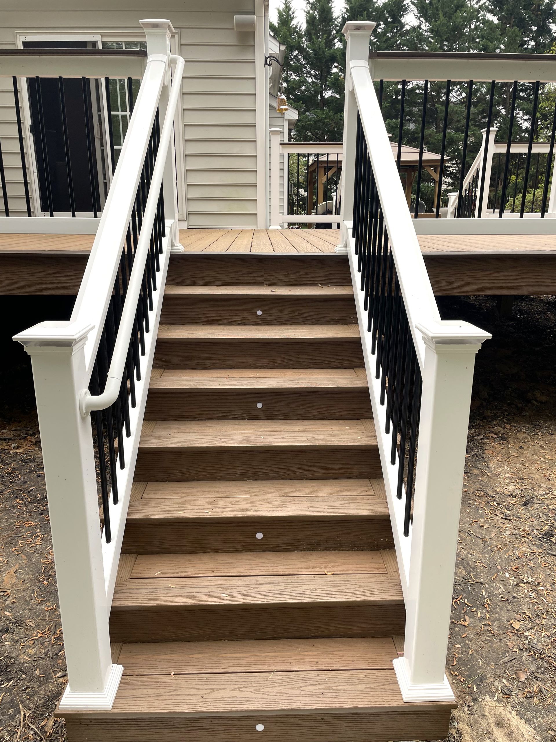 A wooden deck with stairs and a white railing