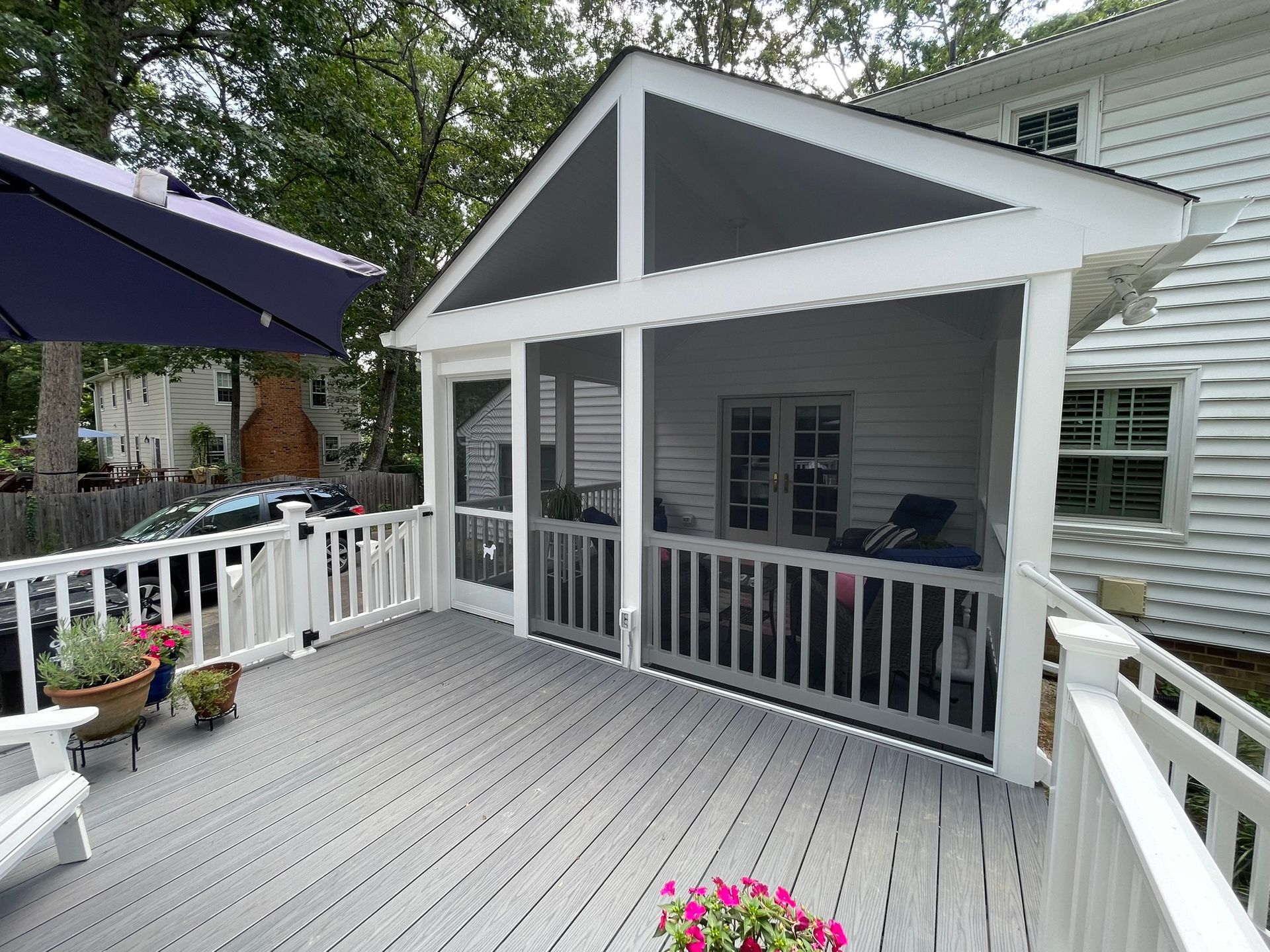 Gray deck with white railing, leading to screened porch. White house exterior visible.