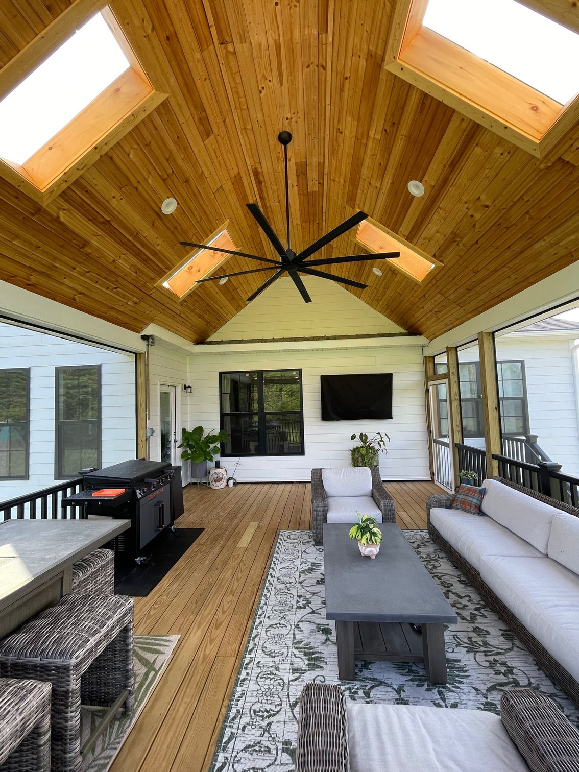 A living room with a ceiling fan and a flat screen tv.