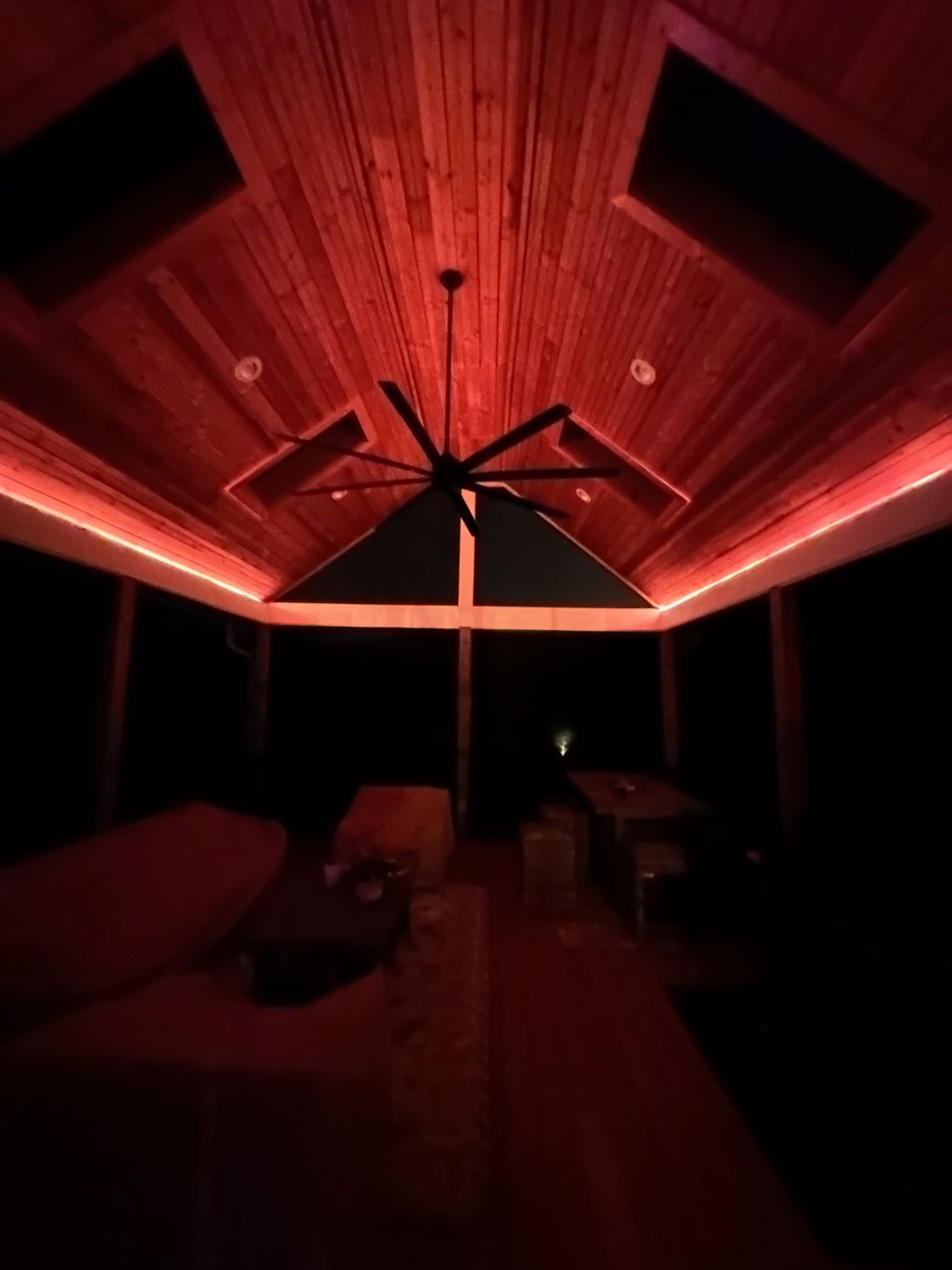 A living room with red lights on the ceiling and a ceiling fan.