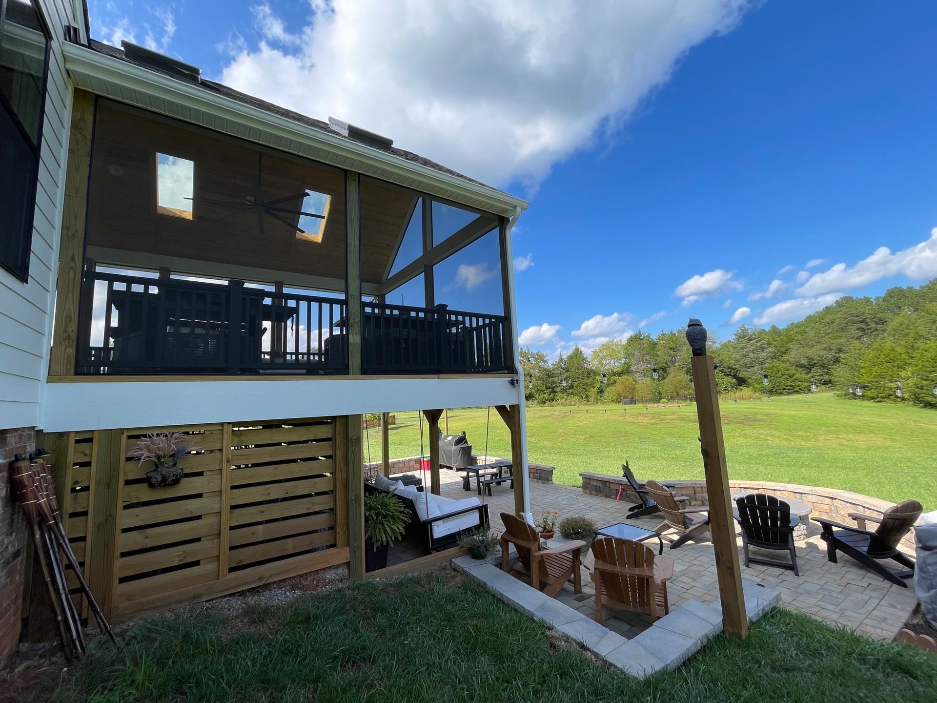 The backyard of a house with a screened in porch and patio area.
