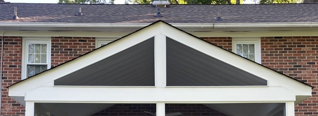 A brick house with a white porch and a black roof.