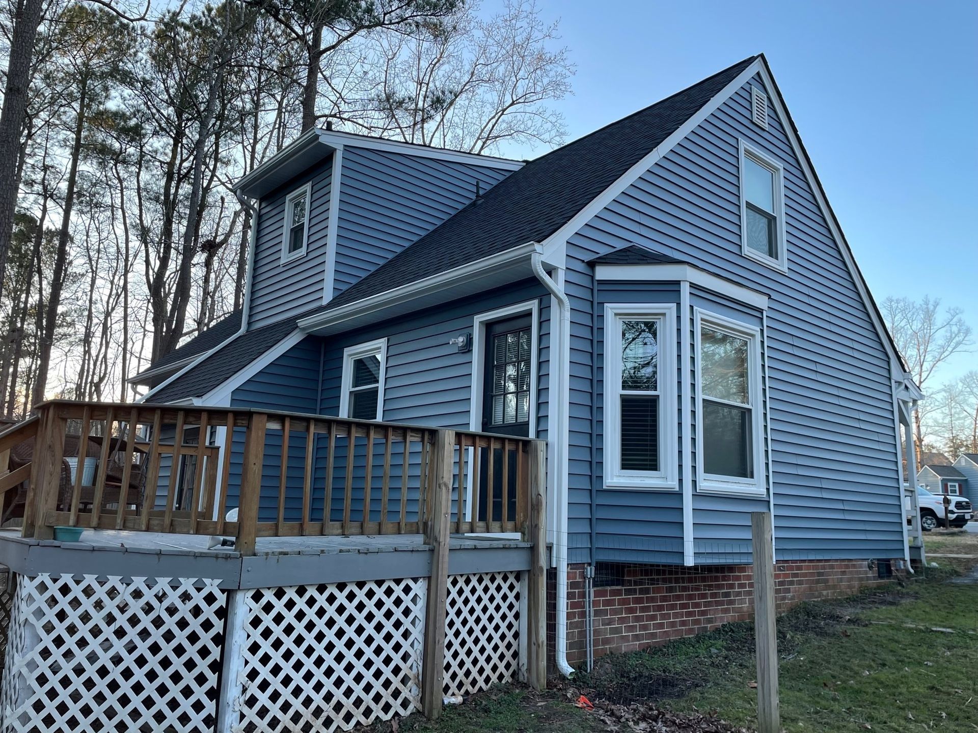 A blue house with a wooden deck in front of it.